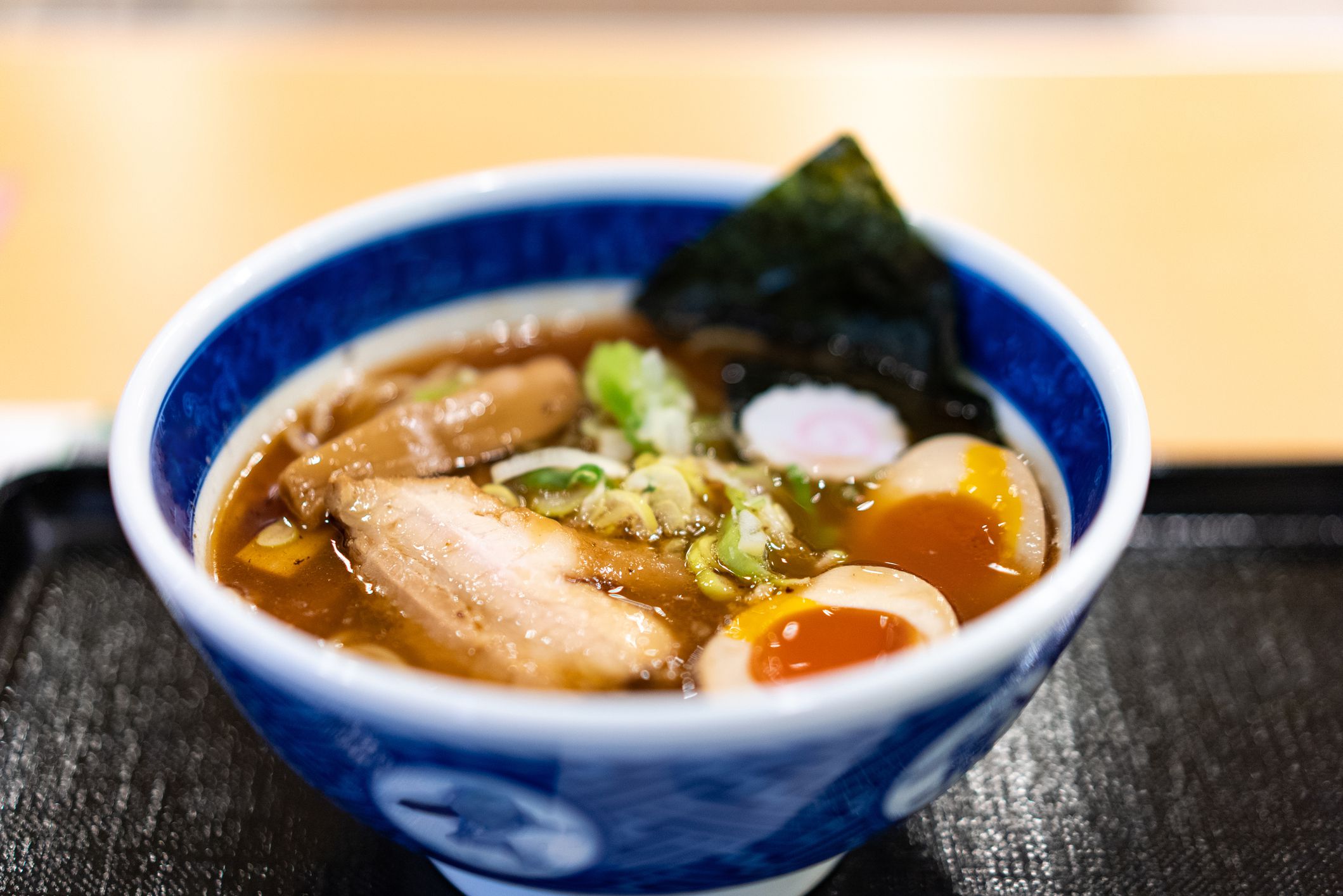 Soy Sauce Ramen with Seafood.A popular Japanese dish.A thick soup of seafood and chicken stock.Toppings:Boiled egg, chashu pork, naruto, green onion, pickled bamboo shoot, nori seaweed.Blue rice bowl.