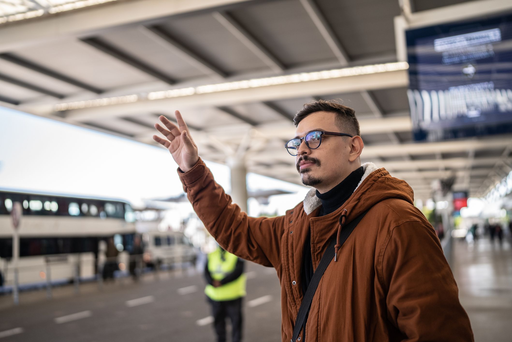 Young man hailing a taxi in an airport