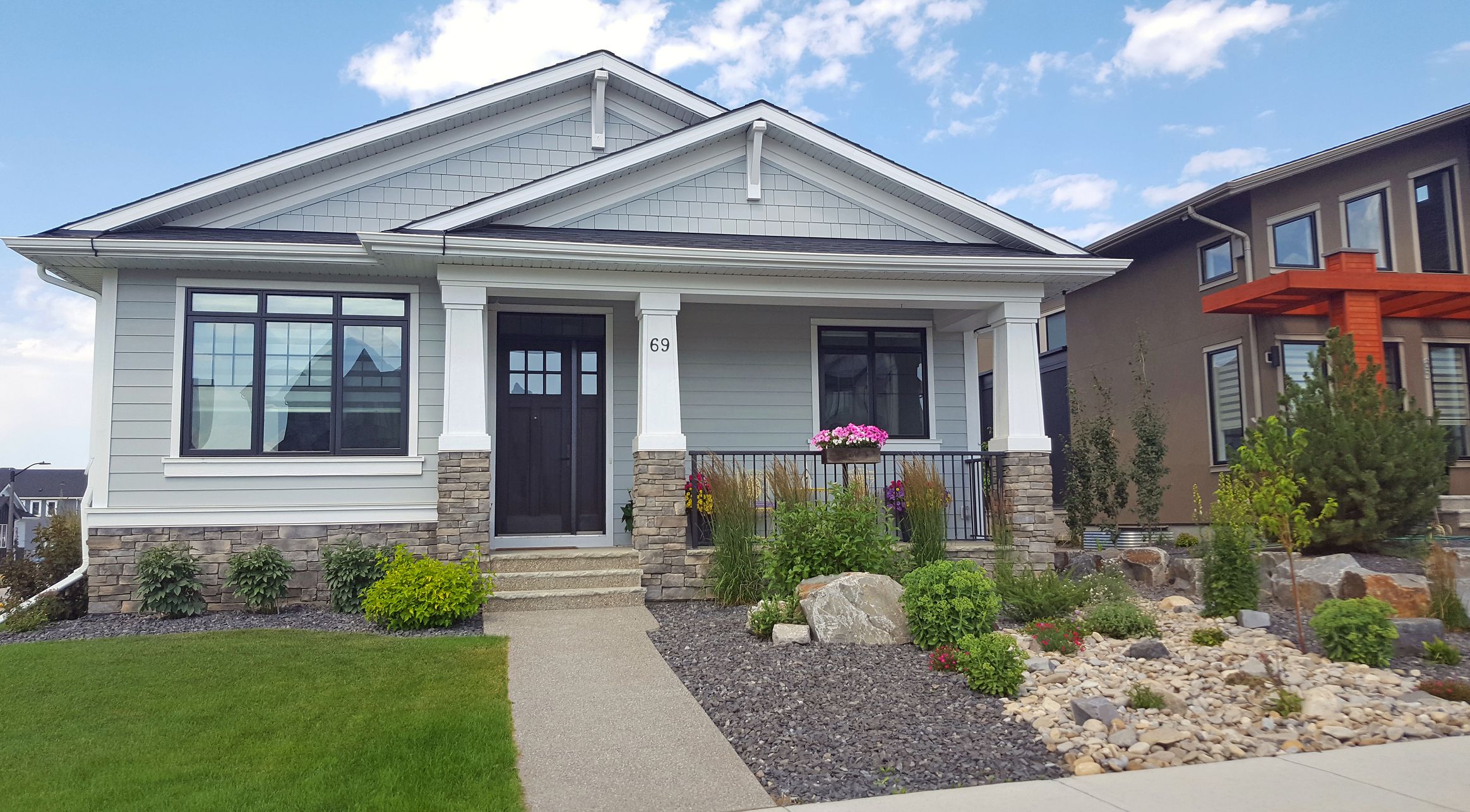 Calgary, Alberta, Canada- July 3,2022: Front view of new 21st century Craftsman shingle style Bungalow. Replicated from early 20th century homes. Easy to care for front yard and garden. Next door to large modern day architecture.