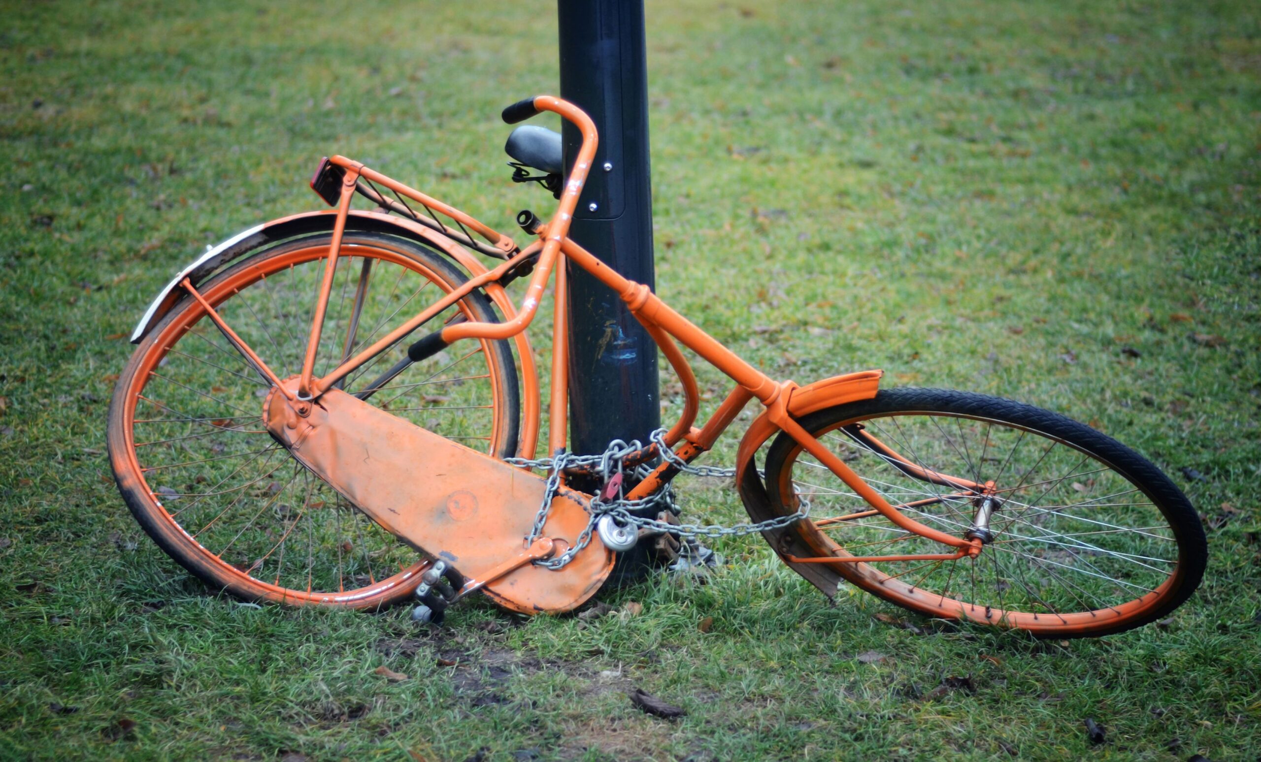 Orange retro bicycle attached to a column