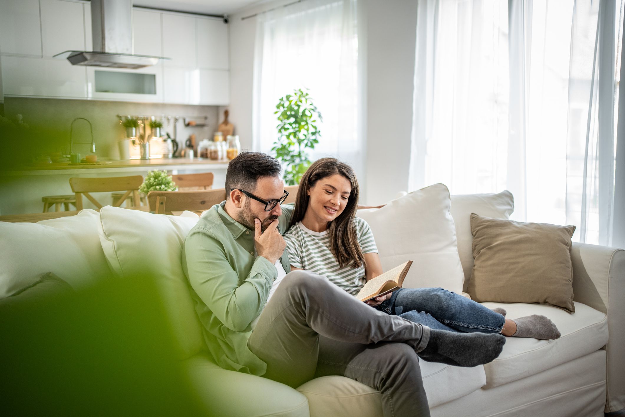 Happy couple sitting on the couch reading together