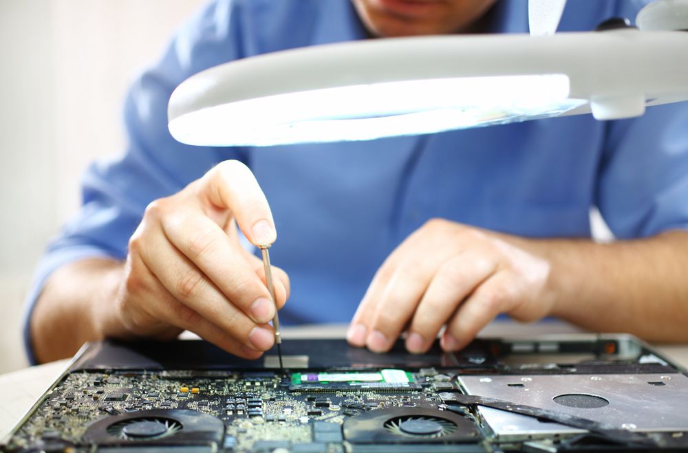 Man unscrewing motherboard of a laptop.