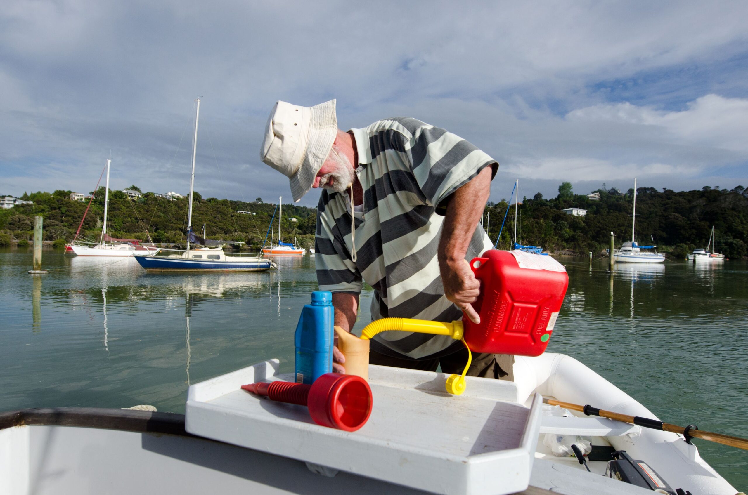 Man pouring fuel into a cup tank of his boat from a red gas canister.