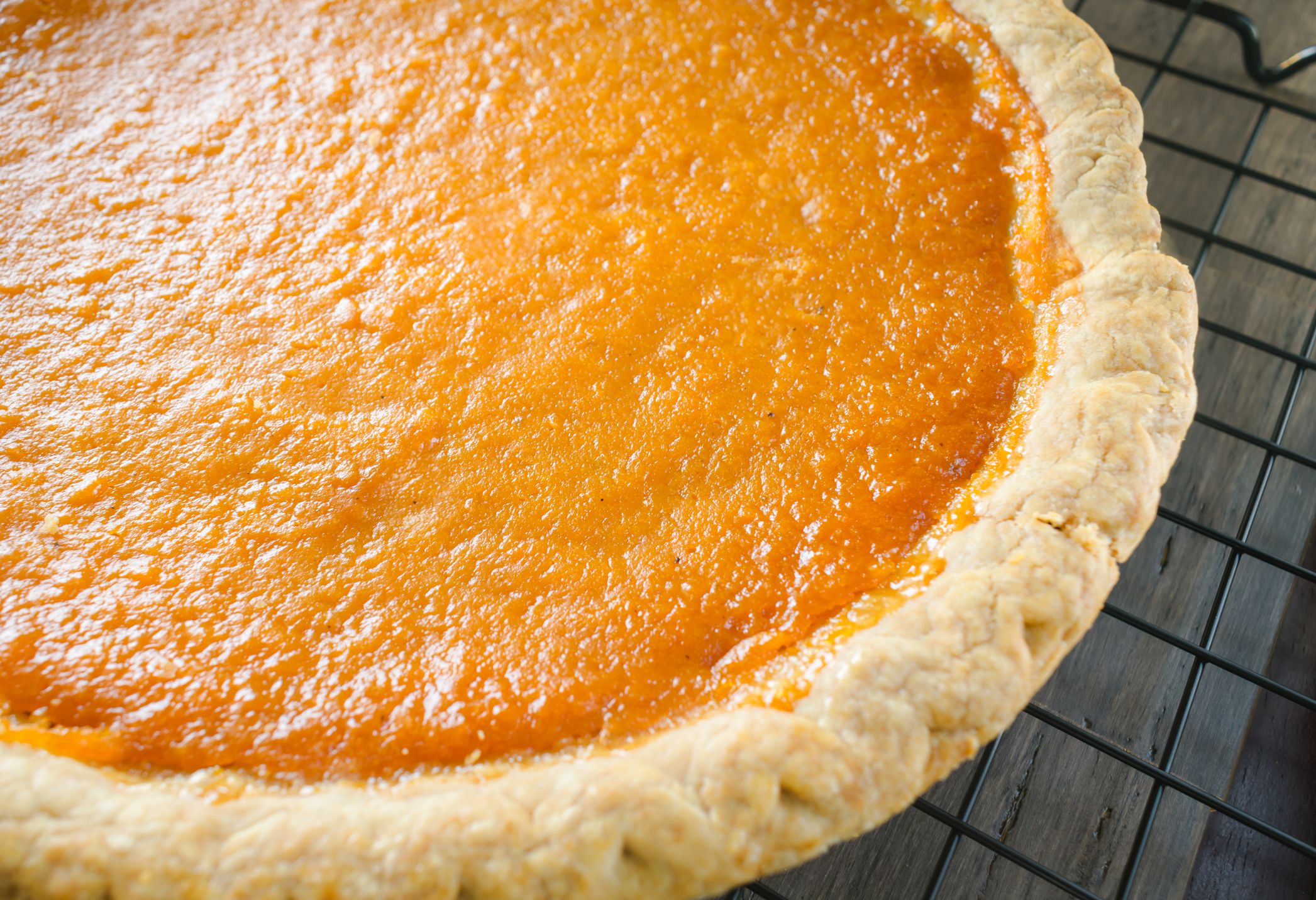 Closeup sweet potato pie cooling on wire rack in kitchen; food useful for thanksgiving , Christmas, and other holidays.