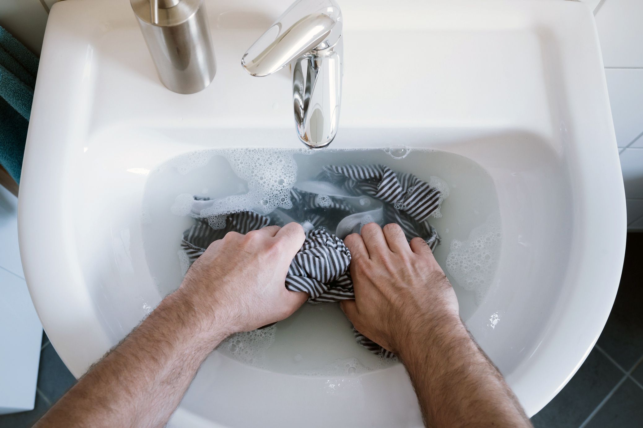 hands wringing clothes in sink
