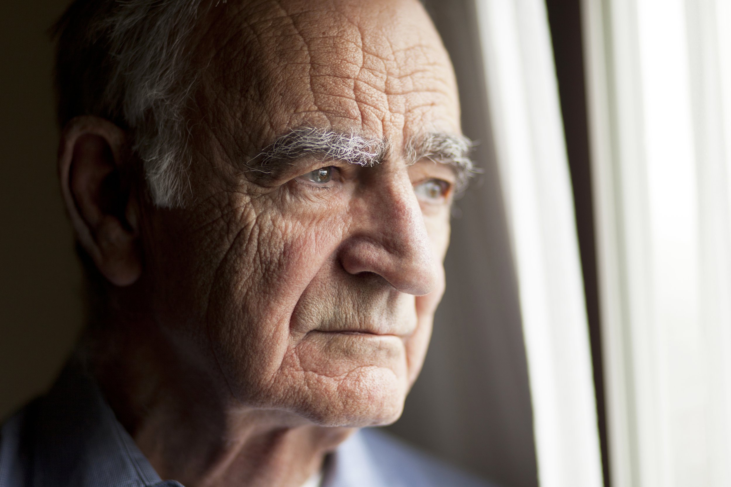 Depressed senior man looking out window
