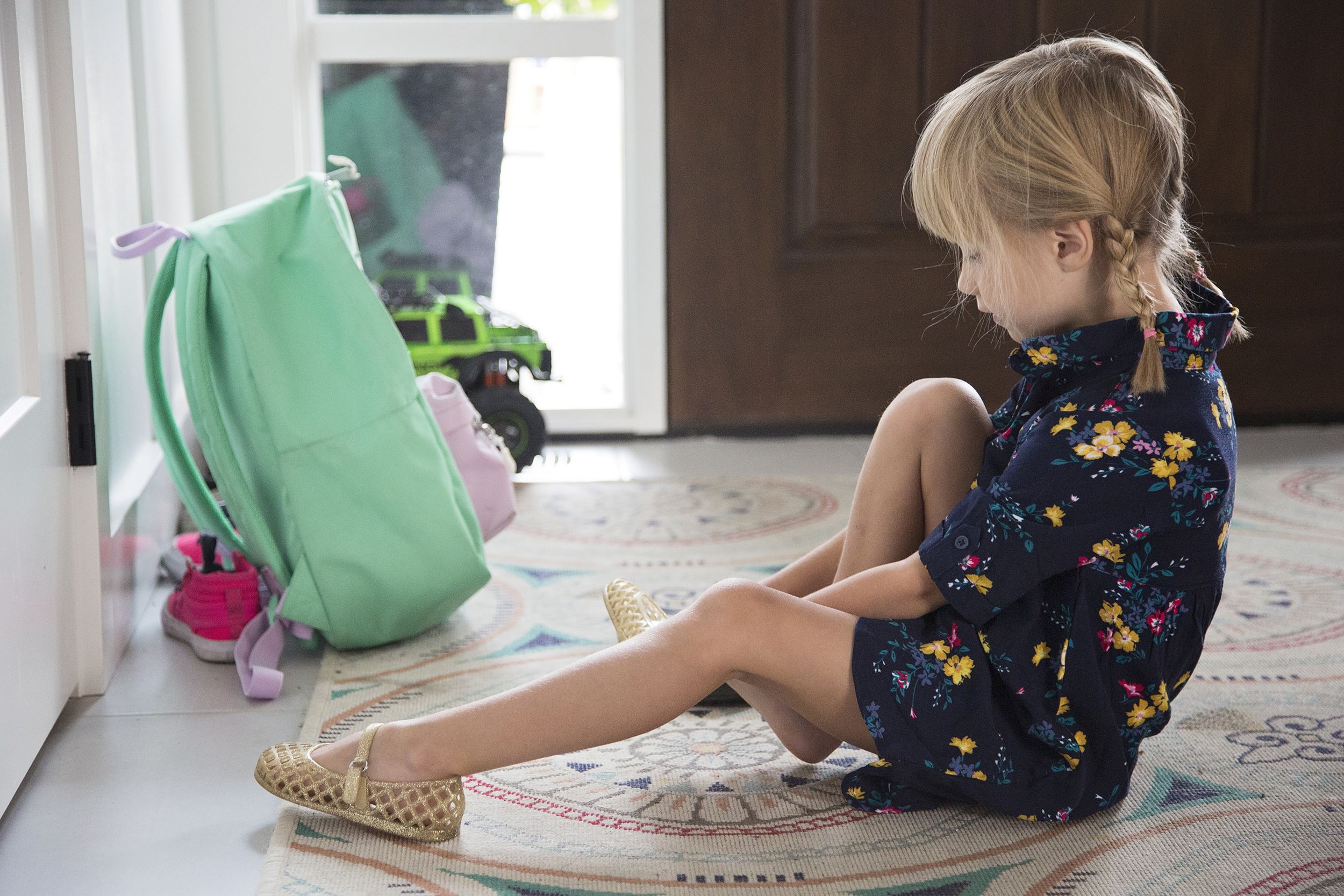 little girl sitting down and putting on shoes