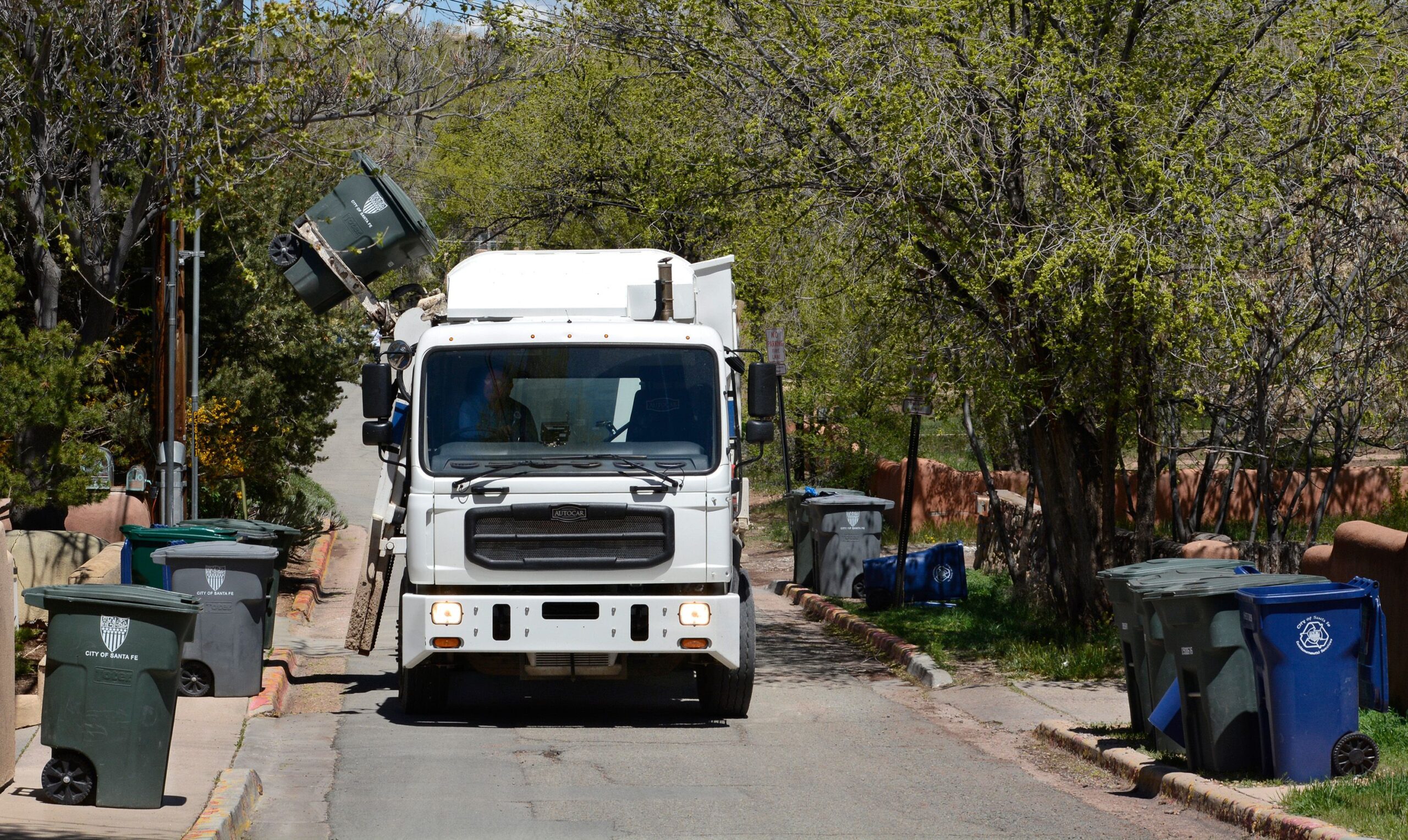 A city garbage truck collects refuse along a street in Santa Fe, New Mexico.