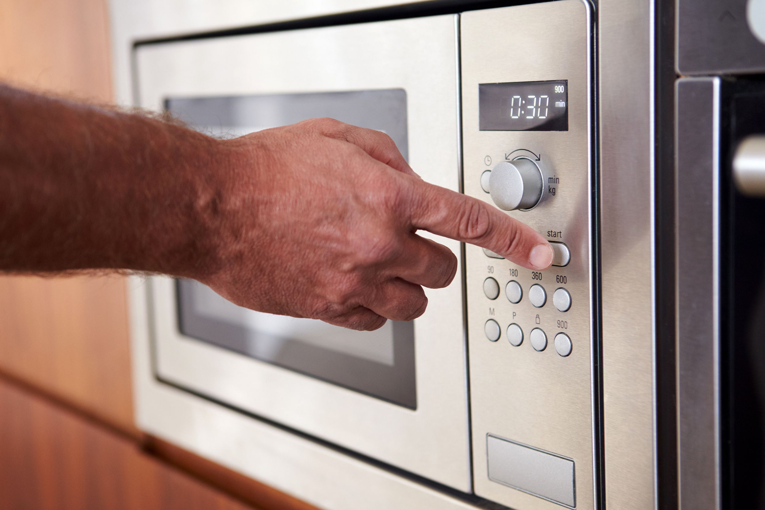 Hand pressing button on microwave