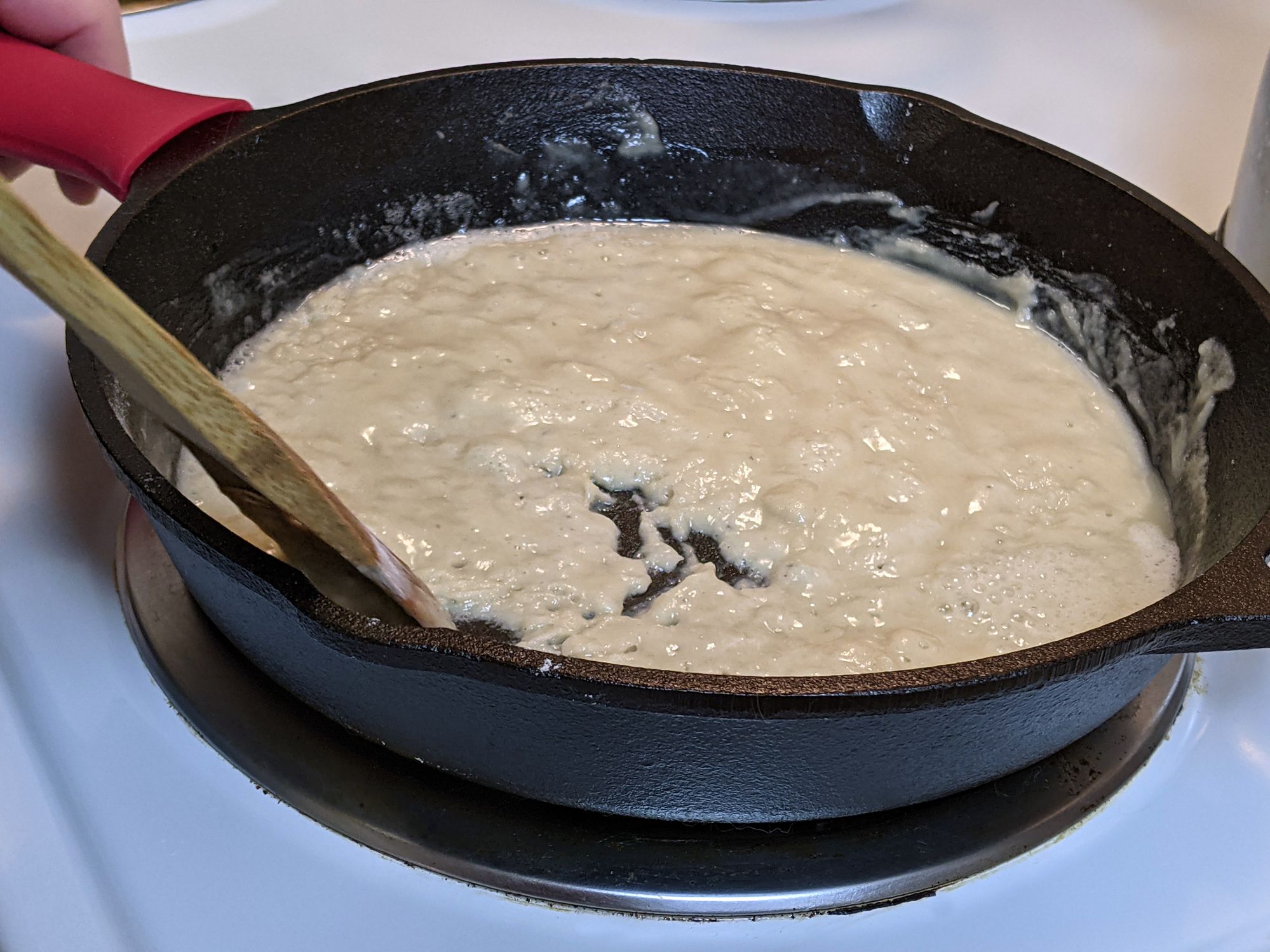 Process of creating a roux out of flour and butter in a cast iron skillet on a stove top
