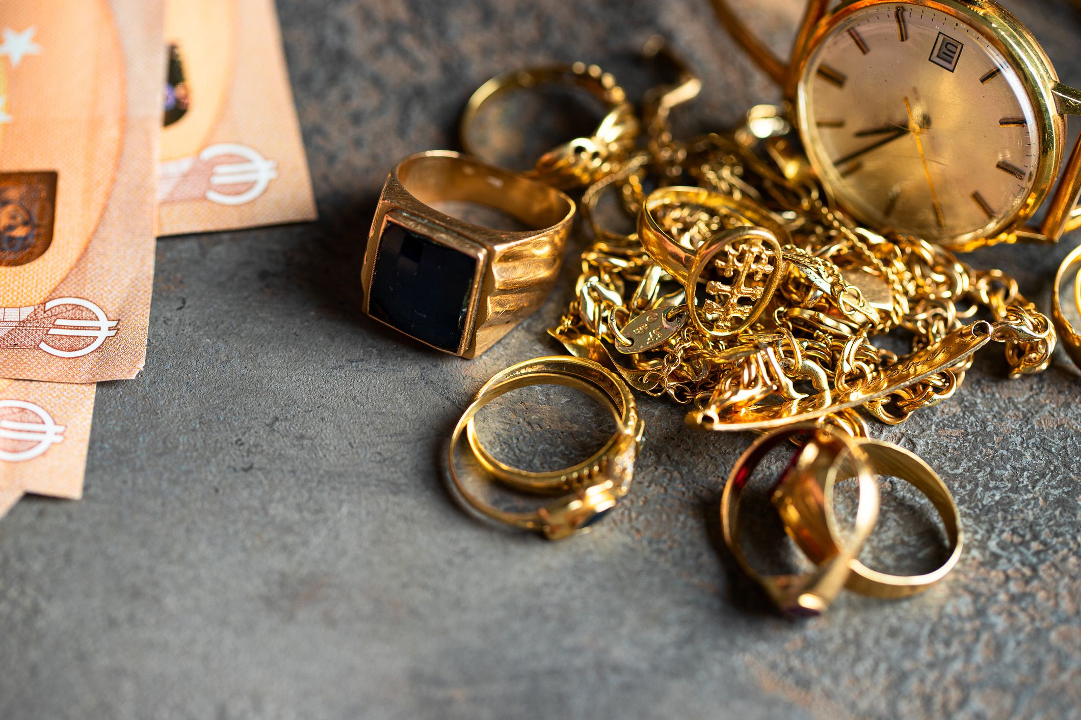 Old and broken jewelry and on Euro banknotes on dark background. Sell gold for money concept.
