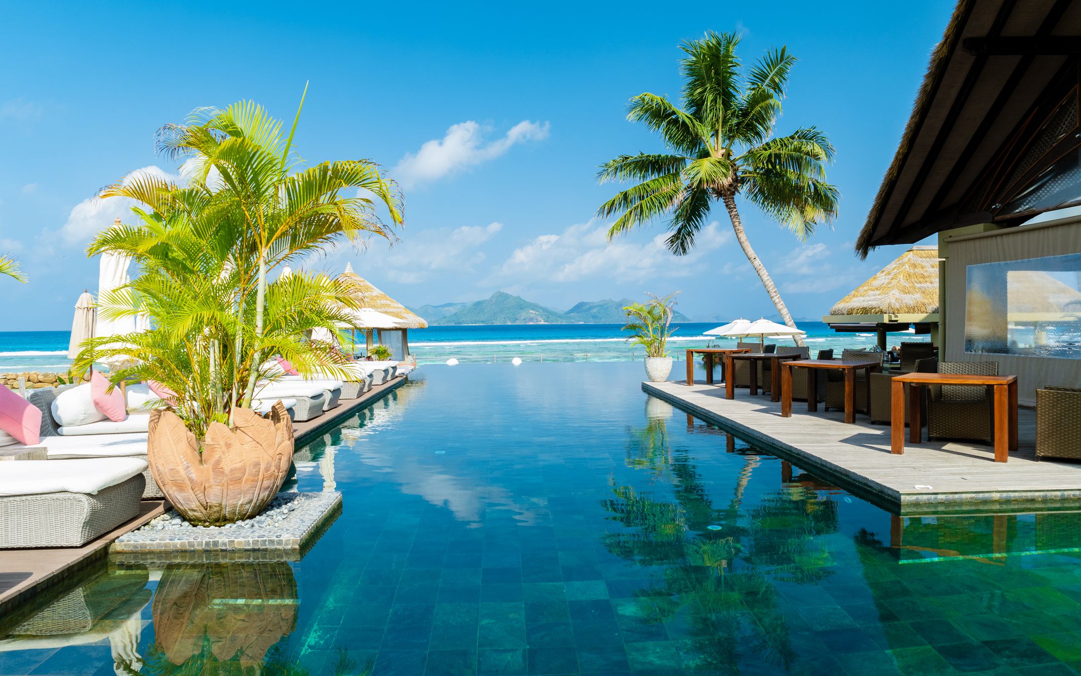 Beach chairs at a swimming pool at a luxury hotel, sun bed, and umbrella.