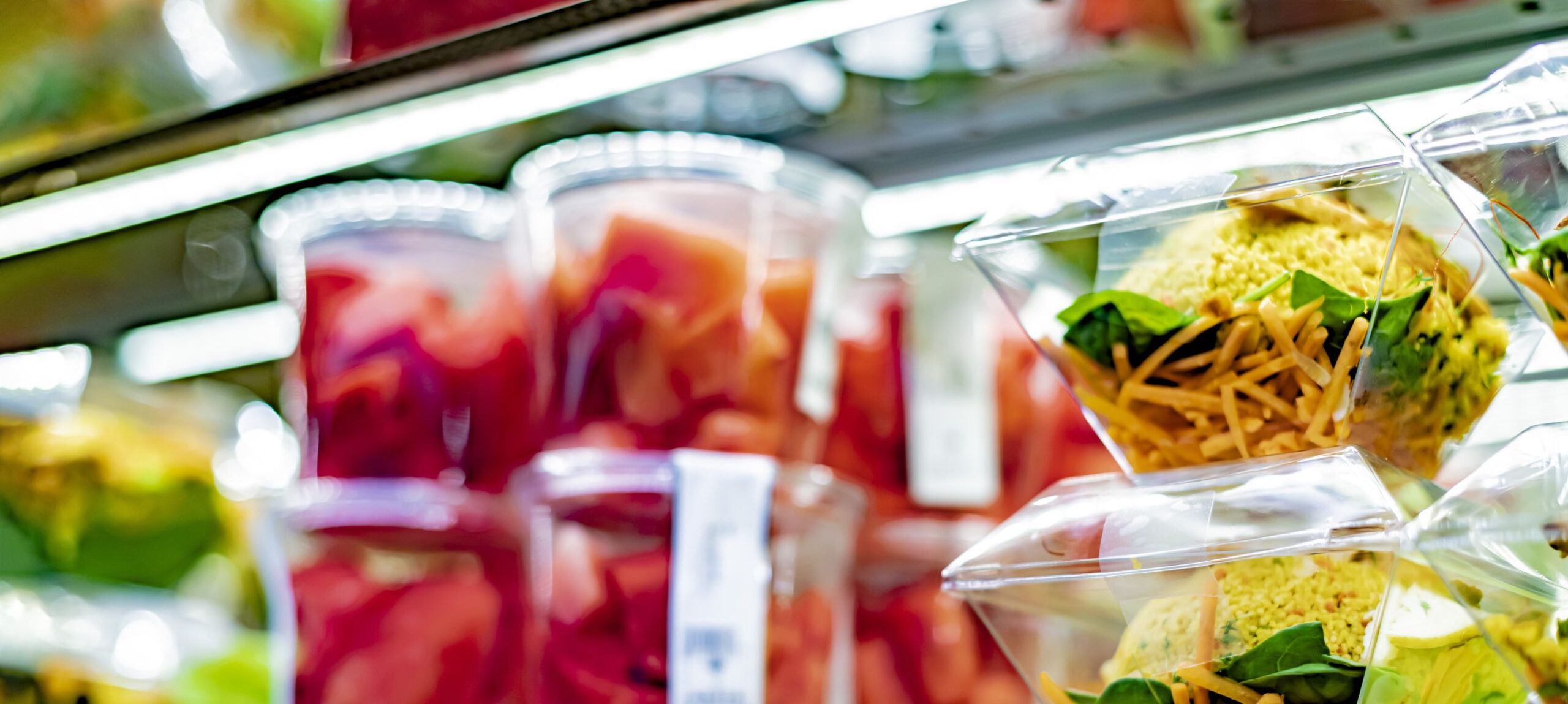 Pre-packaged ready to eat meals and fruit salads displayed in a commercial refrigerator
