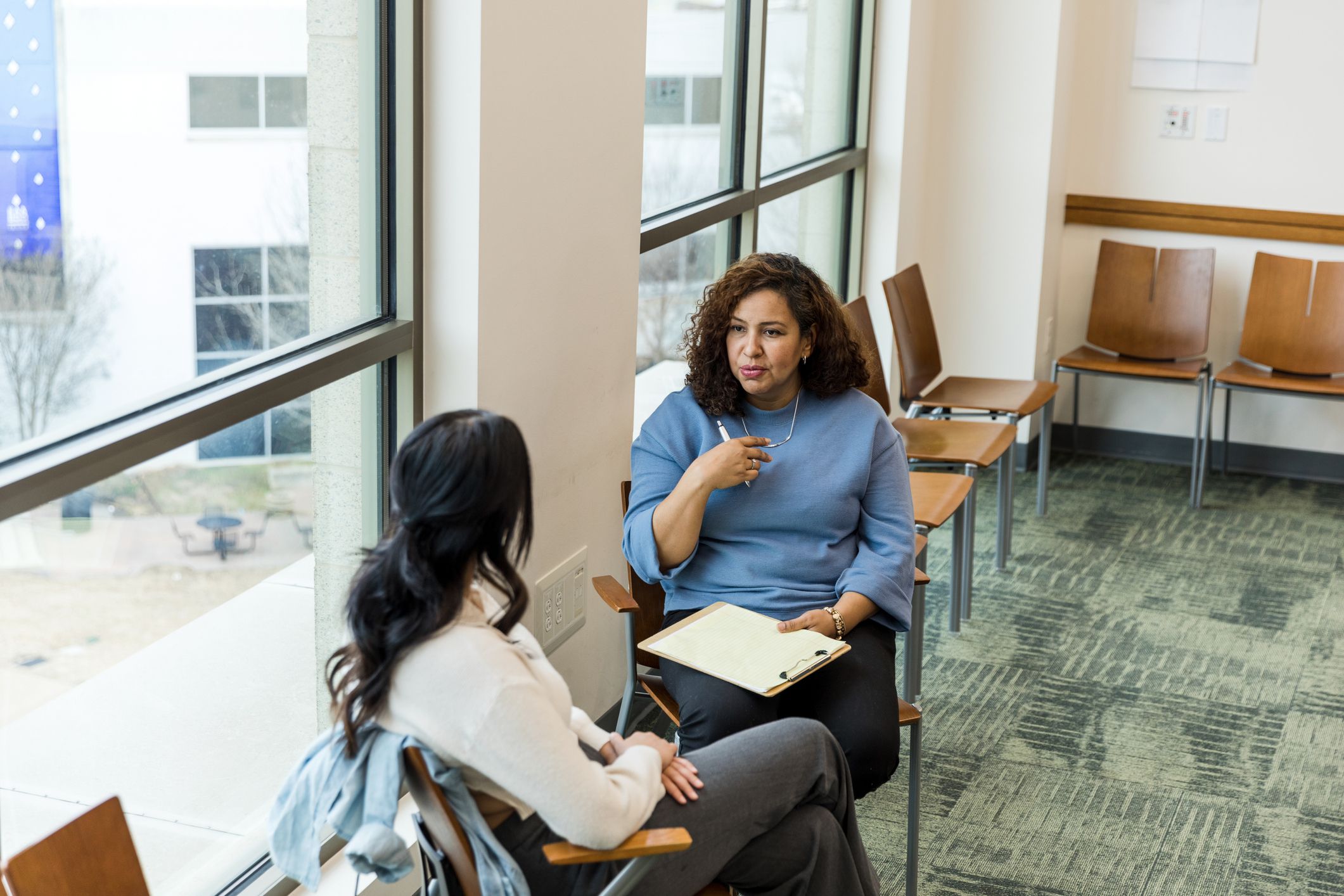 The mature adult female therapist gestures as she gives the unrecognizable woman advice.