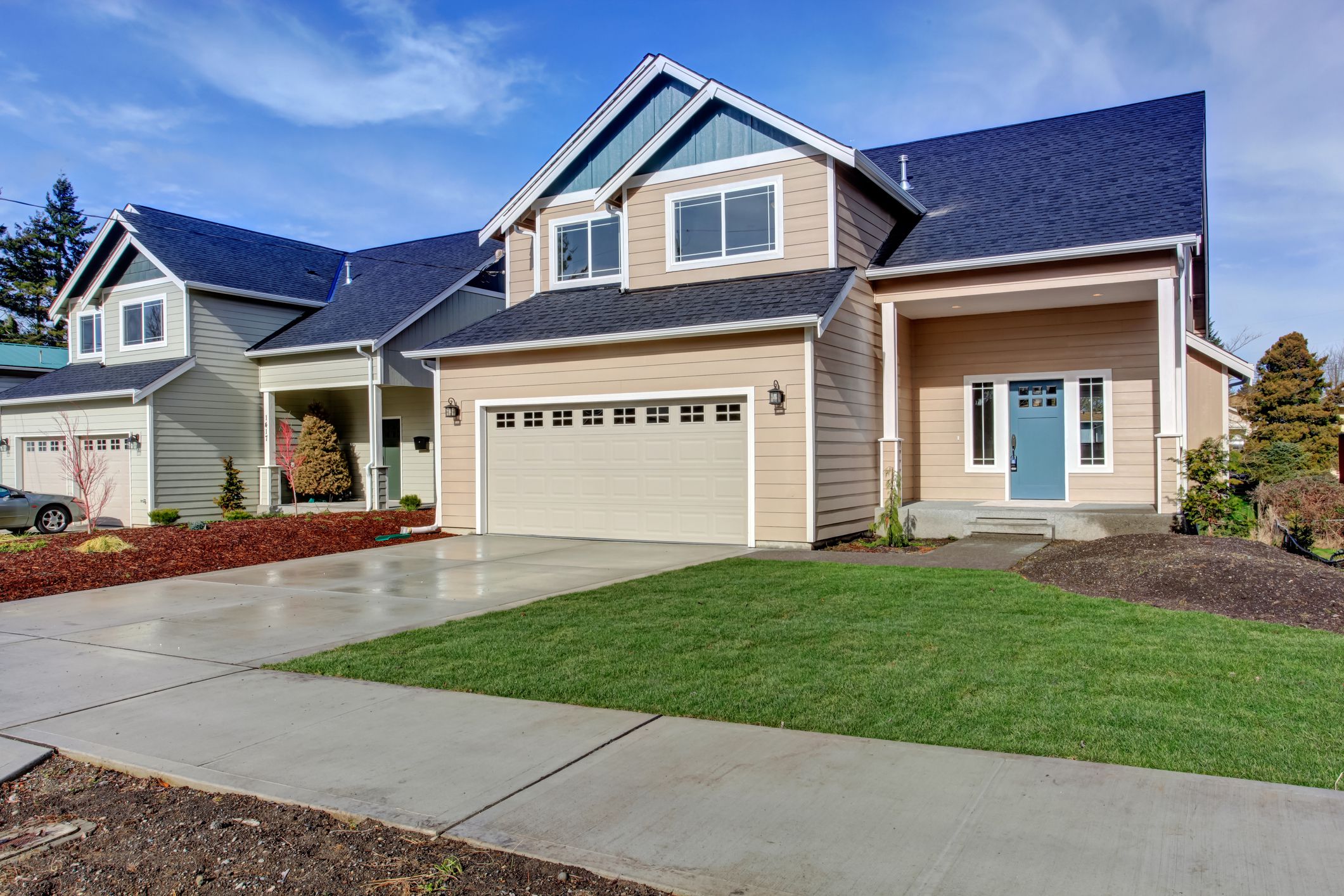 House exterior. American beige house with green grass. Garage with driveway