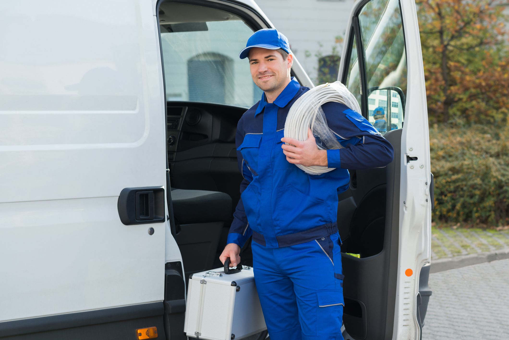Portrait of confident technician with cable coil and toolbox standing outside van