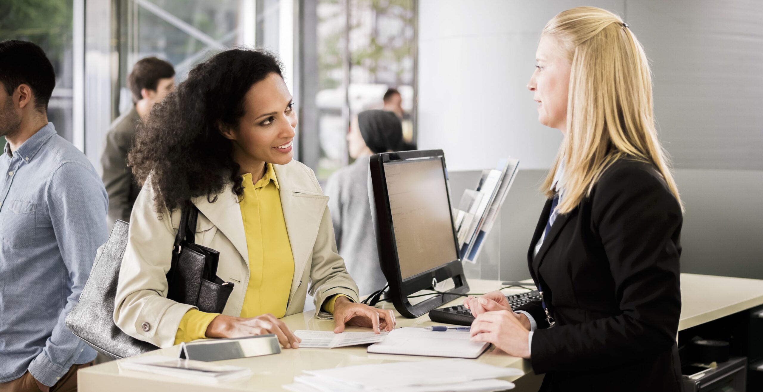 Female bank teller advising female customer for signing document.