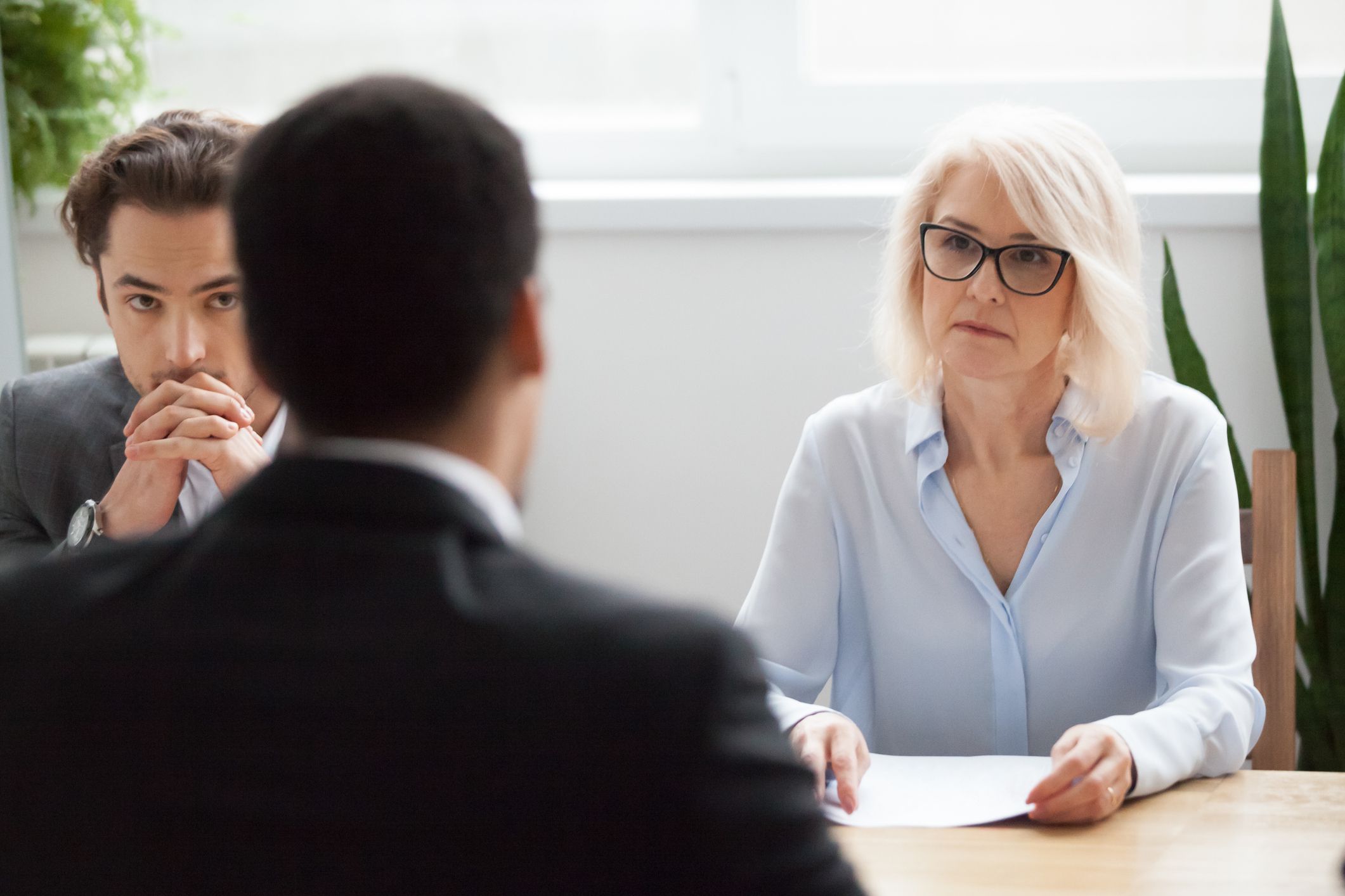Serious attentive senior female hr manager employer listening to candidate at job interview, focused strict mature businesswoman thinking about hiring decision at difficult group negotiations concept