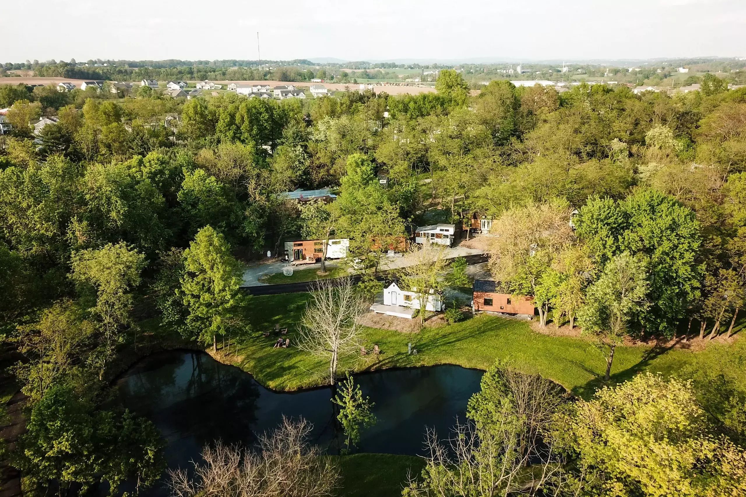 Aerial of Tiny Estates, Elizabethtown, Pennsylvania, surrounded by trees, lake at the bottom, other homes, town, and hills in the distance