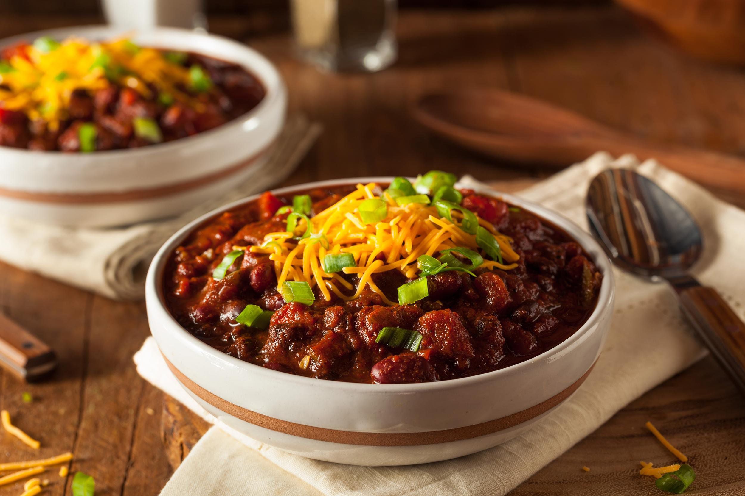 Chili with beans, garnished with shredded cheese and cut scallions