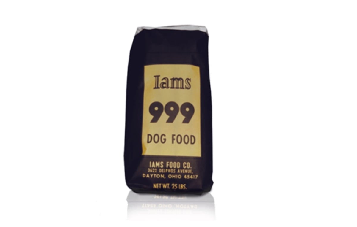 A 25-pound bag of Iams 999 Dog Food with a gold and black label displays the brand name, product name, and company address—plus a nod to companies founded by year—all standing upright on a white background.
