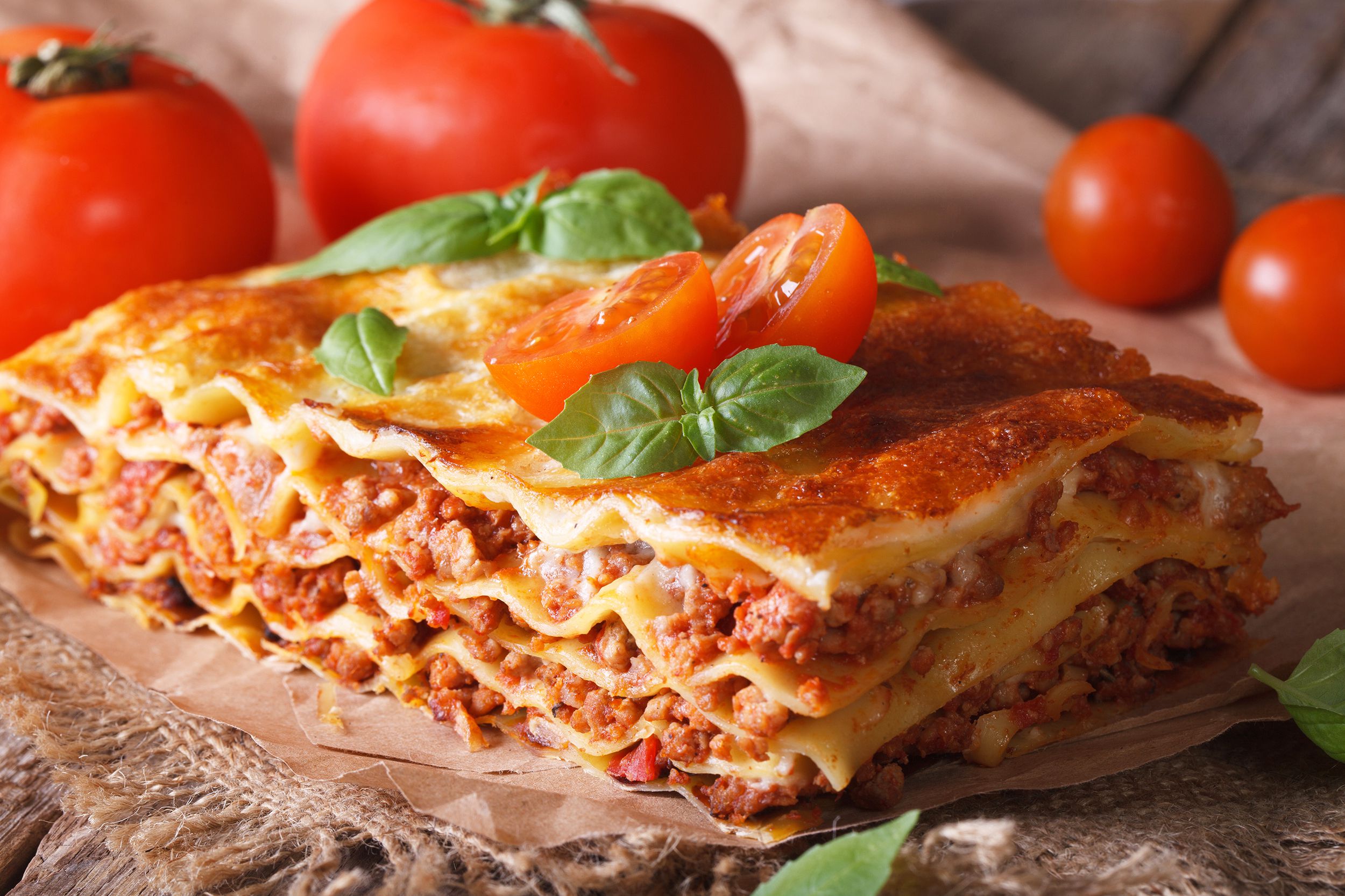 Lasagna garnished with fresh plum tomatoes and fresh basil
