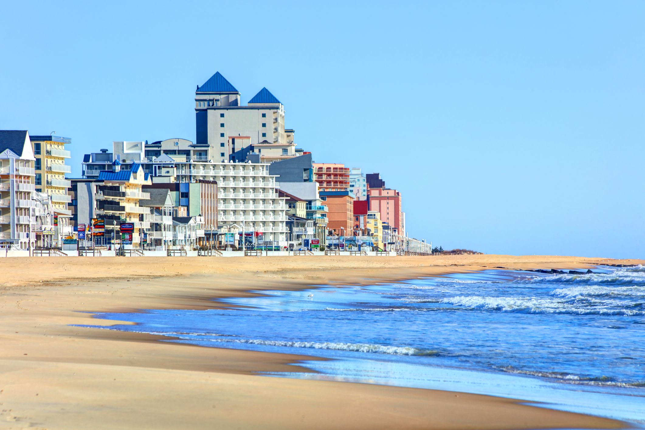 Empty beach with ocean during off-season, Ocean City Beach, Ocean City, Maryland, hotels and buildings in the background with a light blue sky