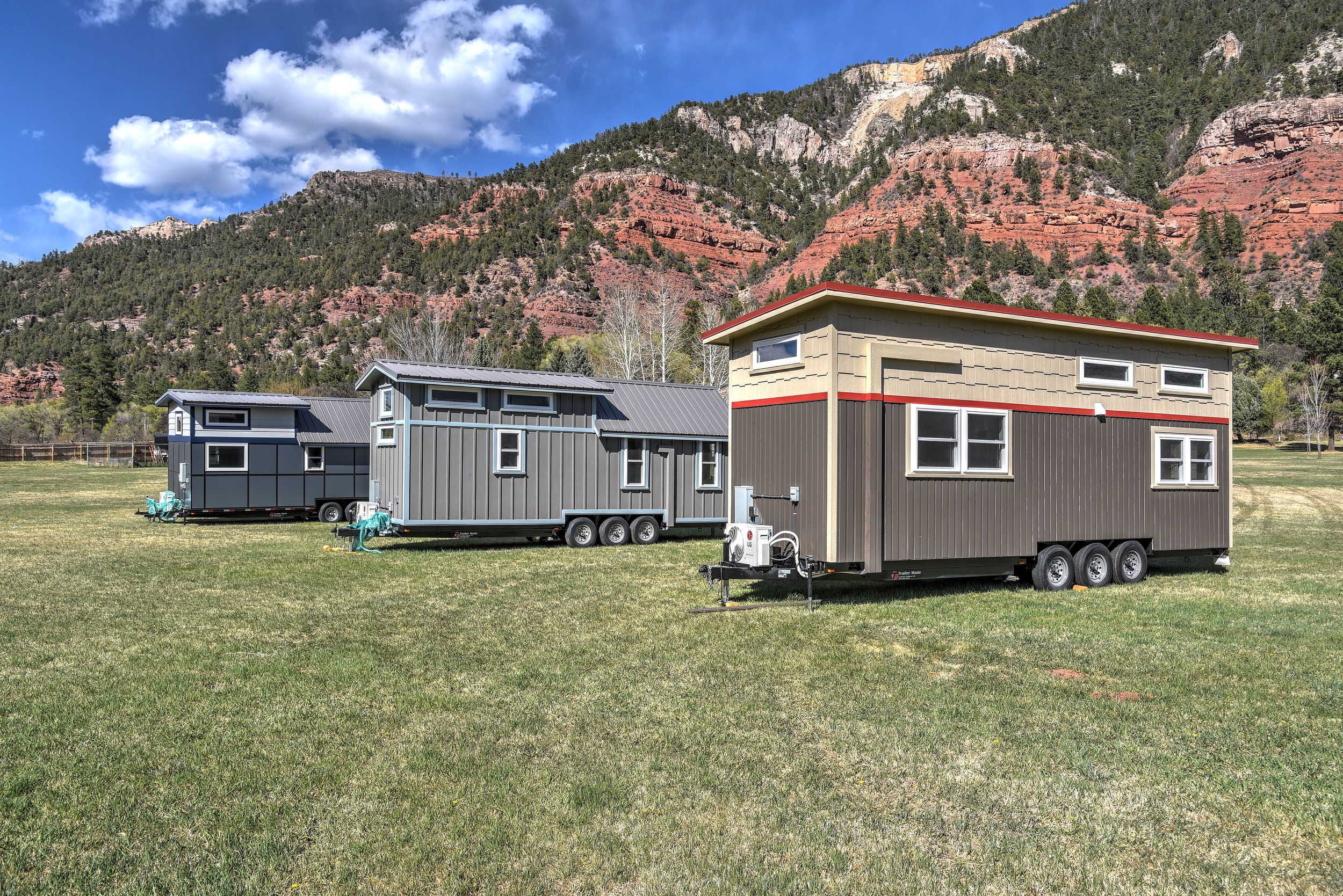 Three tiny homes in Escalante Village, Durango, Colorado, with mountains in the background on a sunny day