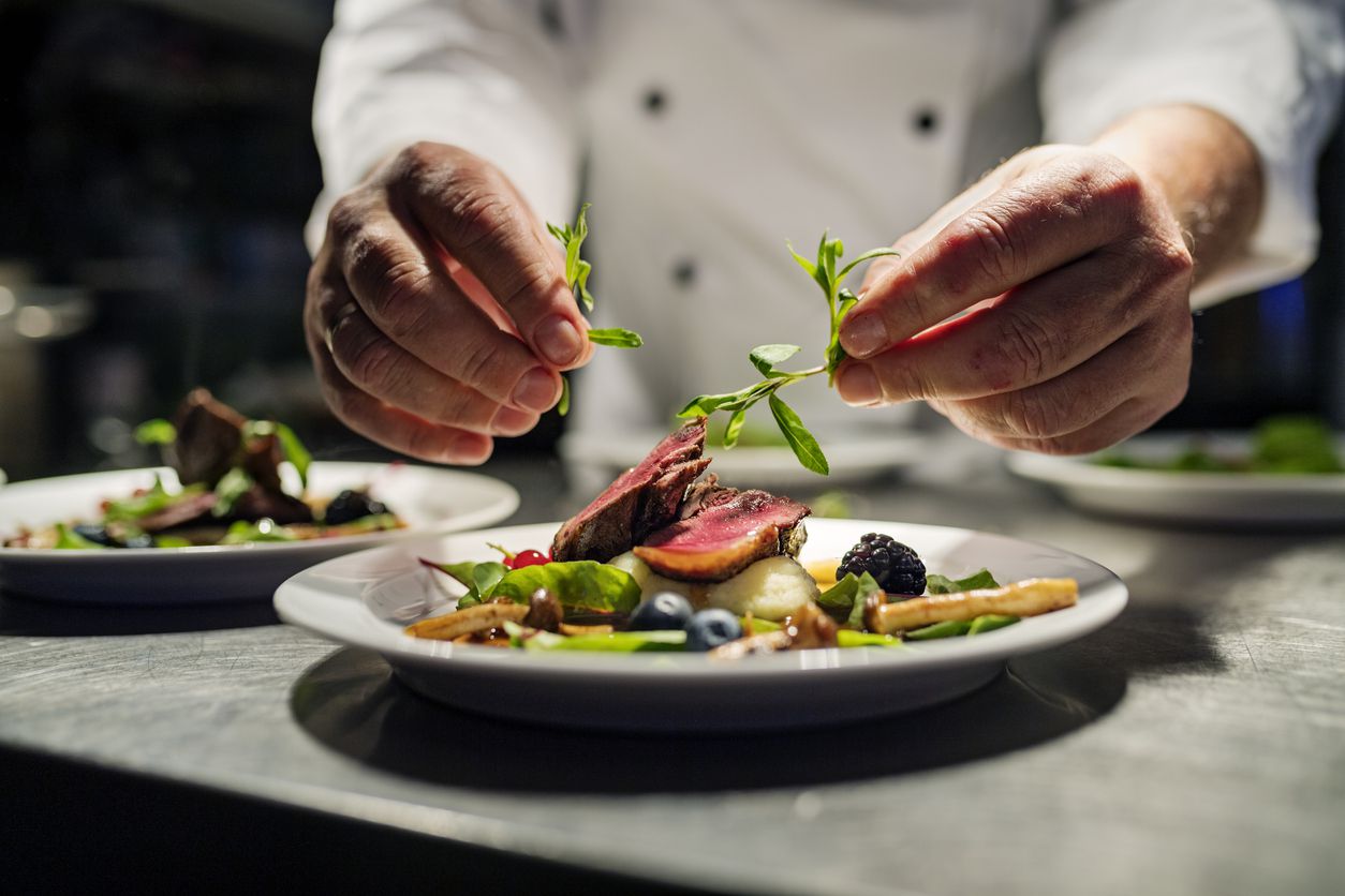 chef garnishing plate with a gourmet meal