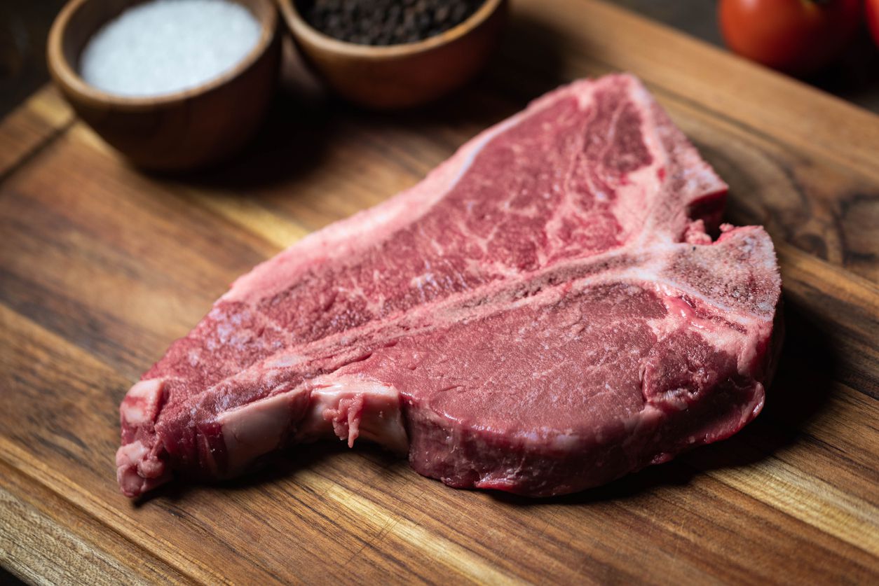 fresh t-bone steak on wooden cutting board with