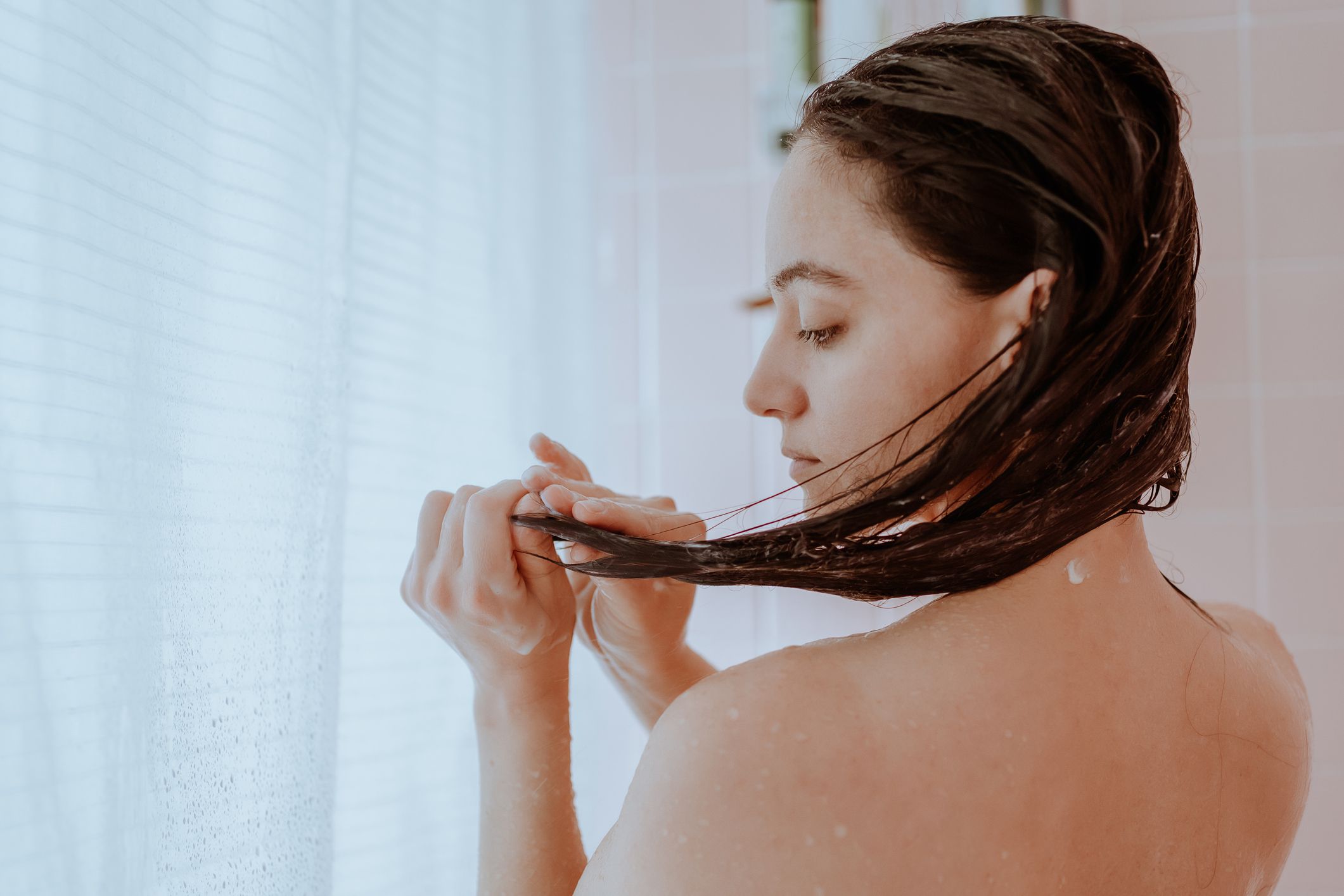 Woman taking a shower and washing her hair at home