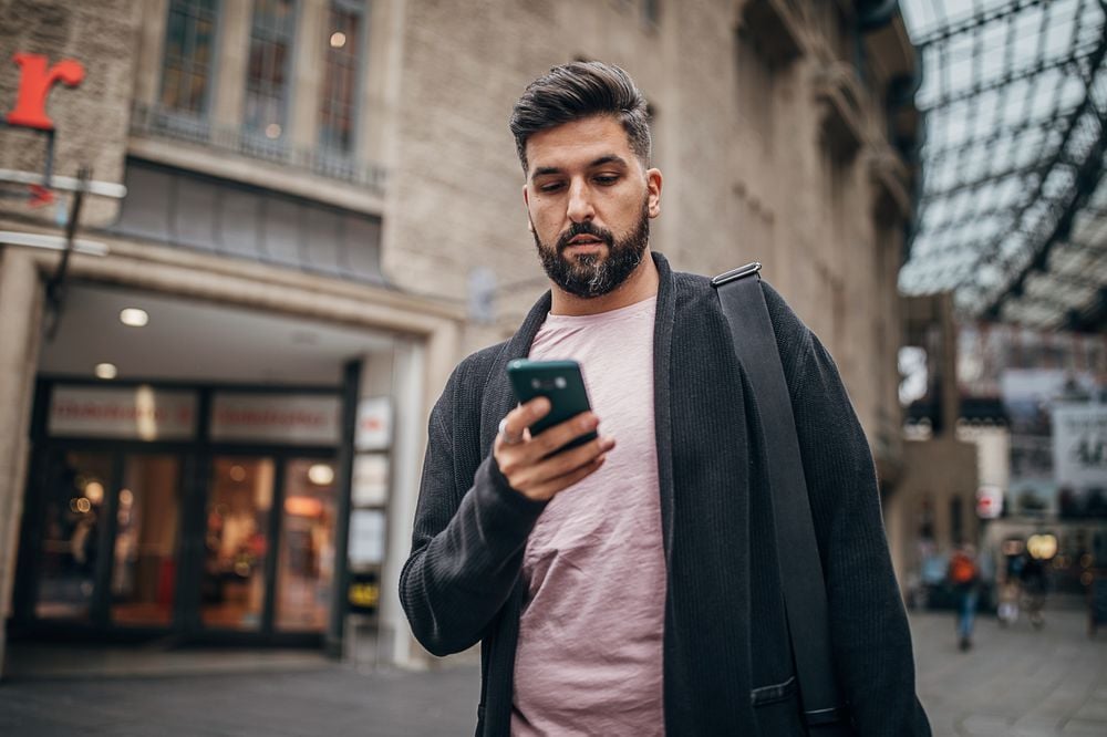 Modern man in city using mobile phone
