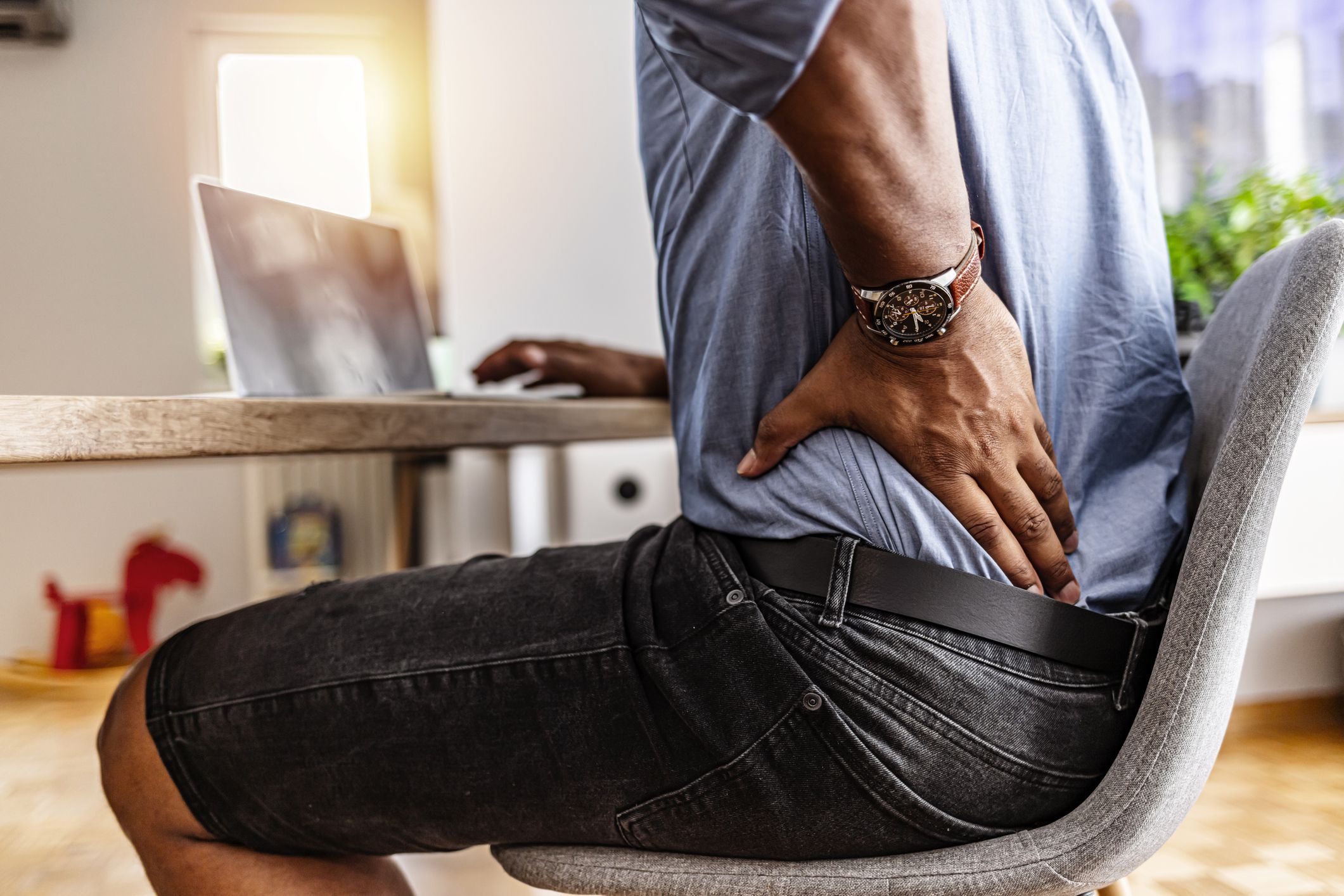 Shot of a young businessman suffering from a backache while working at his desk in his office.