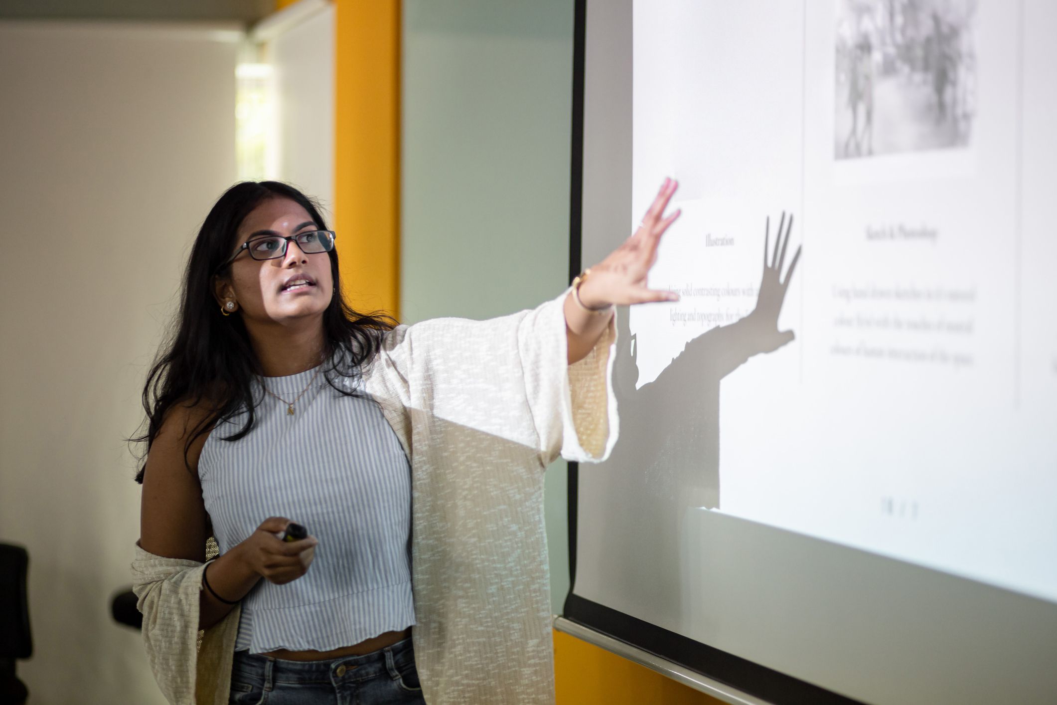 Asian college student is making a presentation in front of projector screen