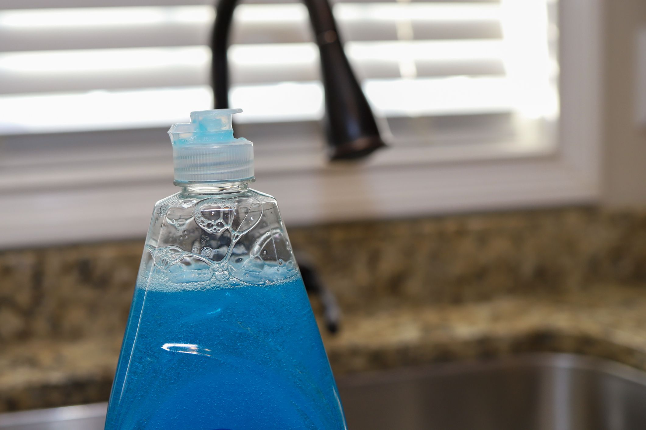 A bottle of dish detergent sitting on a kitchen sink