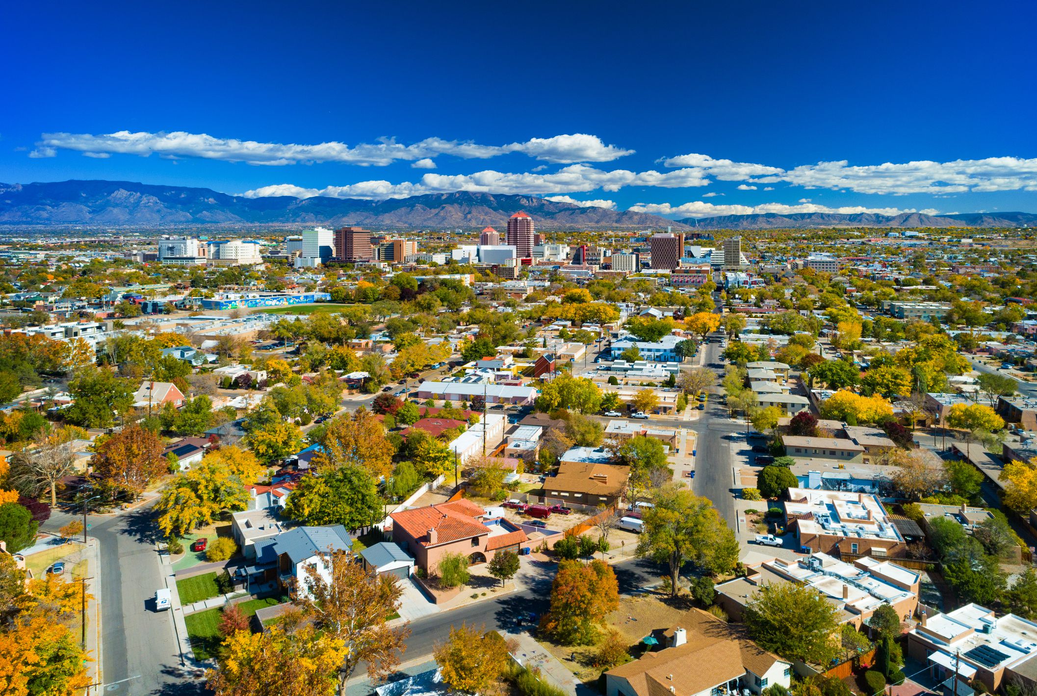Downtown Albuquerque skyline aerial view with neighborhoods in the foreground and the Sandia Mountain Range in the background. Photo was taken in autumn.