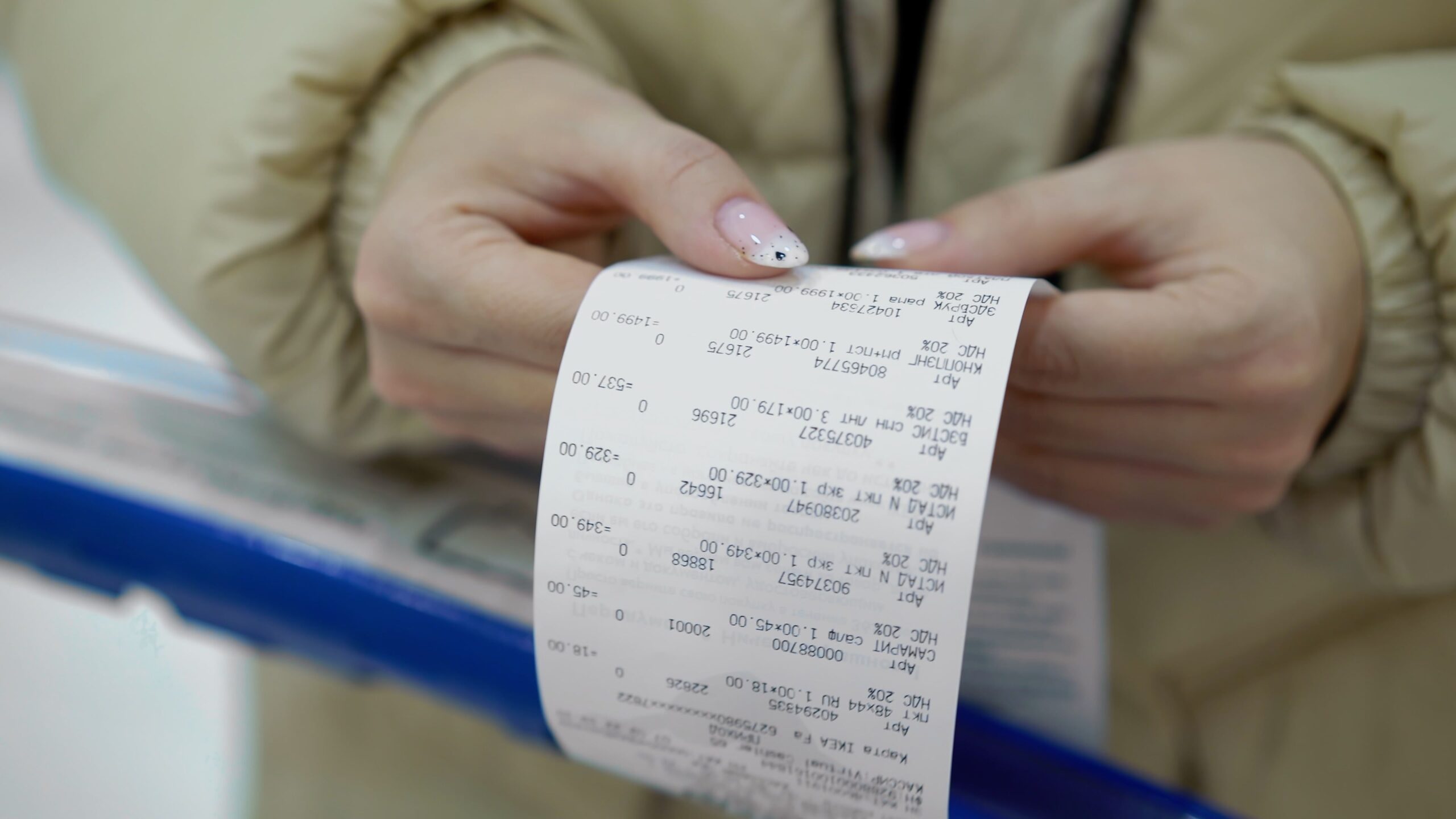 The buyer holds a purchase receipt in his hands, checks purchases and prices. Woman in a supermarket with a shopping cart. Girl with paper bill in store.