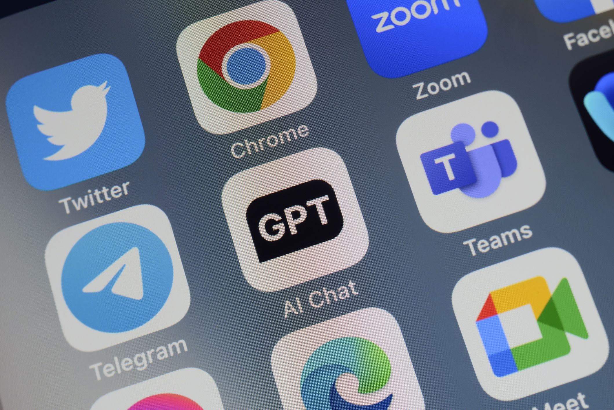 Close-up of of the icon of the ChatGPT artificial intelligence chatbot app logo on a cellphone screen. Surrounded by the app icons of Twitter, Chrome, Zoom, Telegram, Teams, Edge and Meet.