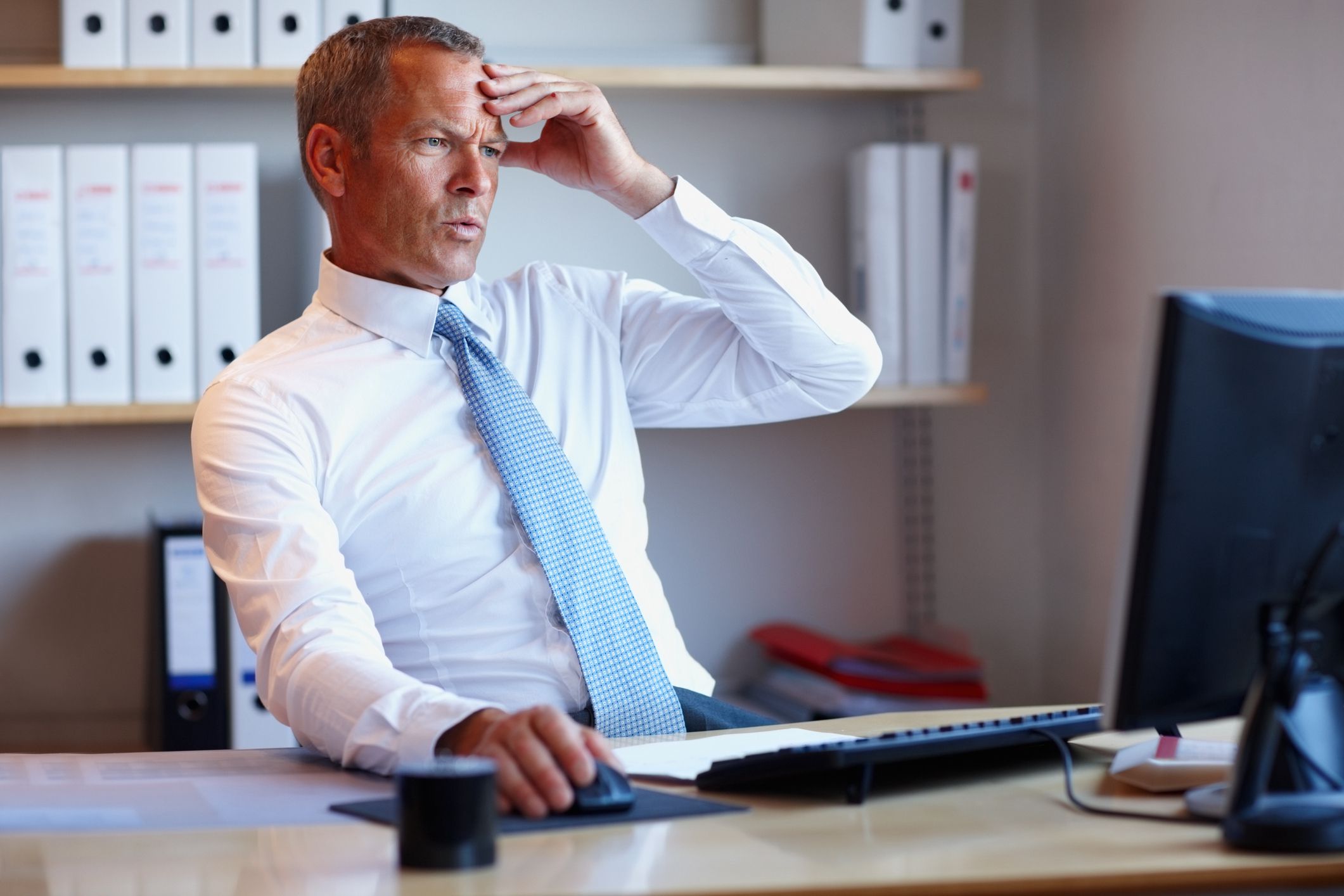 Disappointed mature businessman looking at computer screen in the office