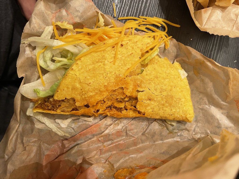 A smashed hard shell taco from Taco Bell with beef, cheese, and lettuce.