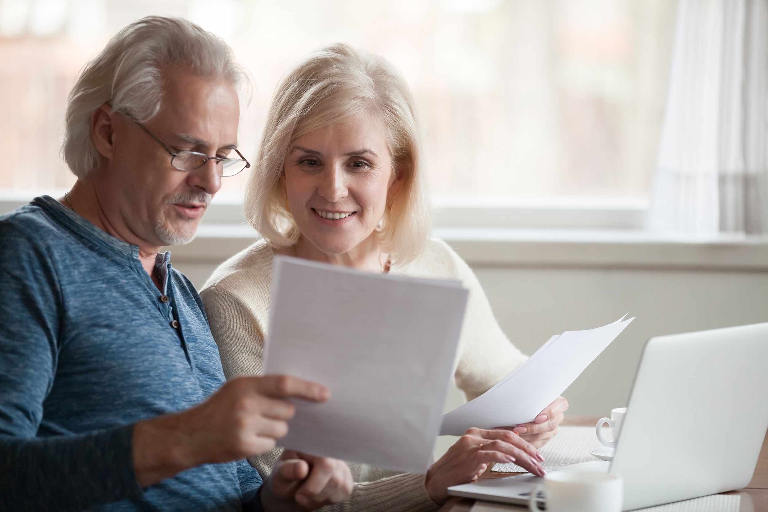 happy older aged couple holding reading good news in document
