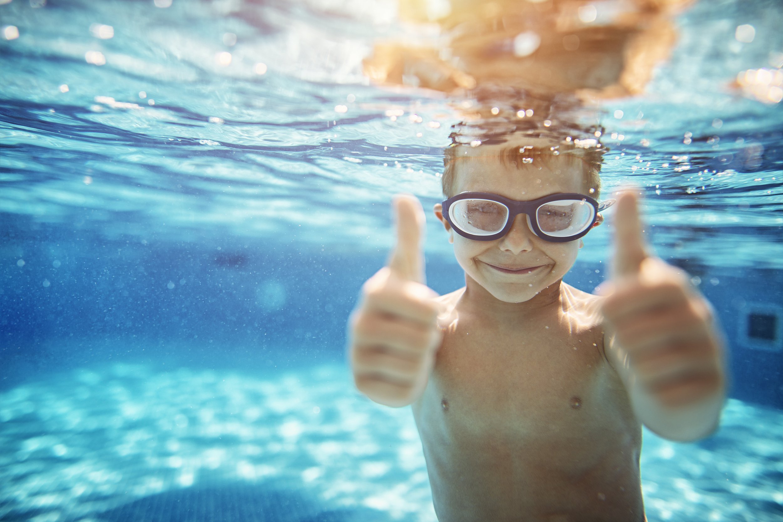 little boy in pool showing thumbs up
