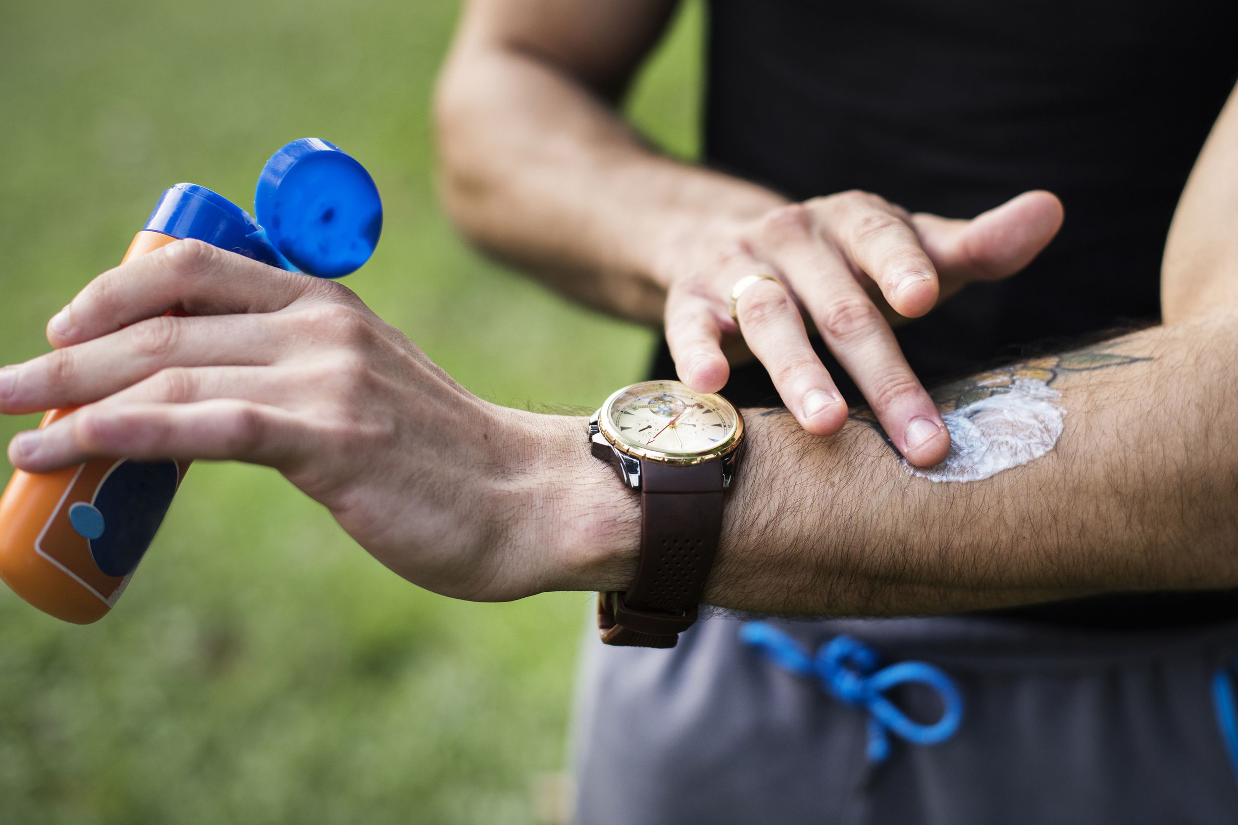 man putting on sunscreen outside, on break from exercising