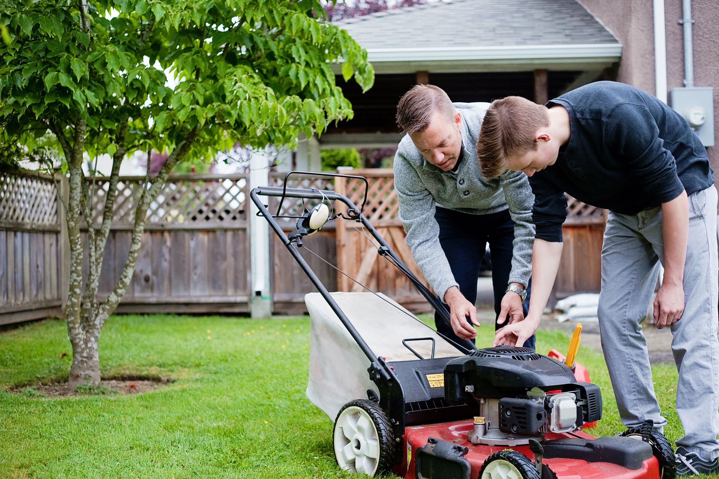 son learning how to mow the lawn with father