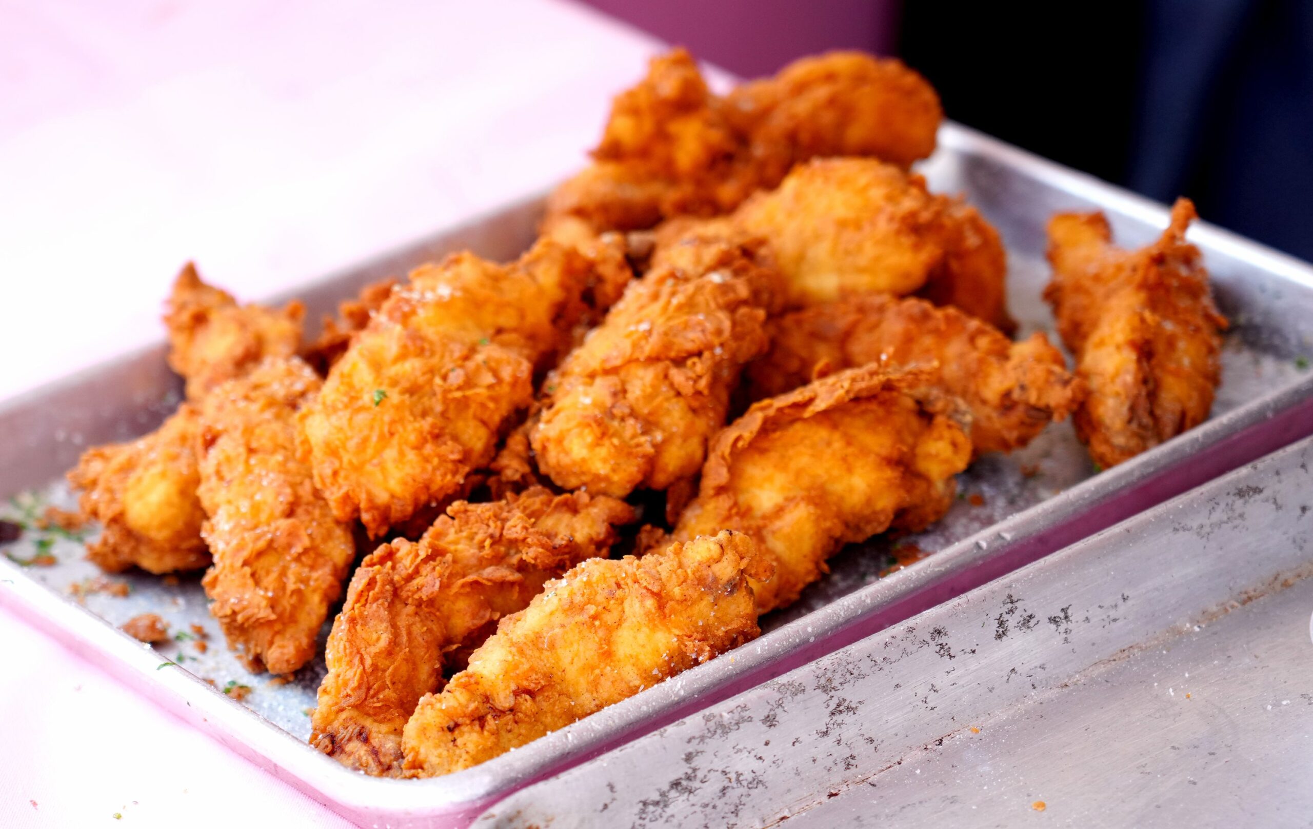 A close up image of several chicken tenders on a small baking sheet
