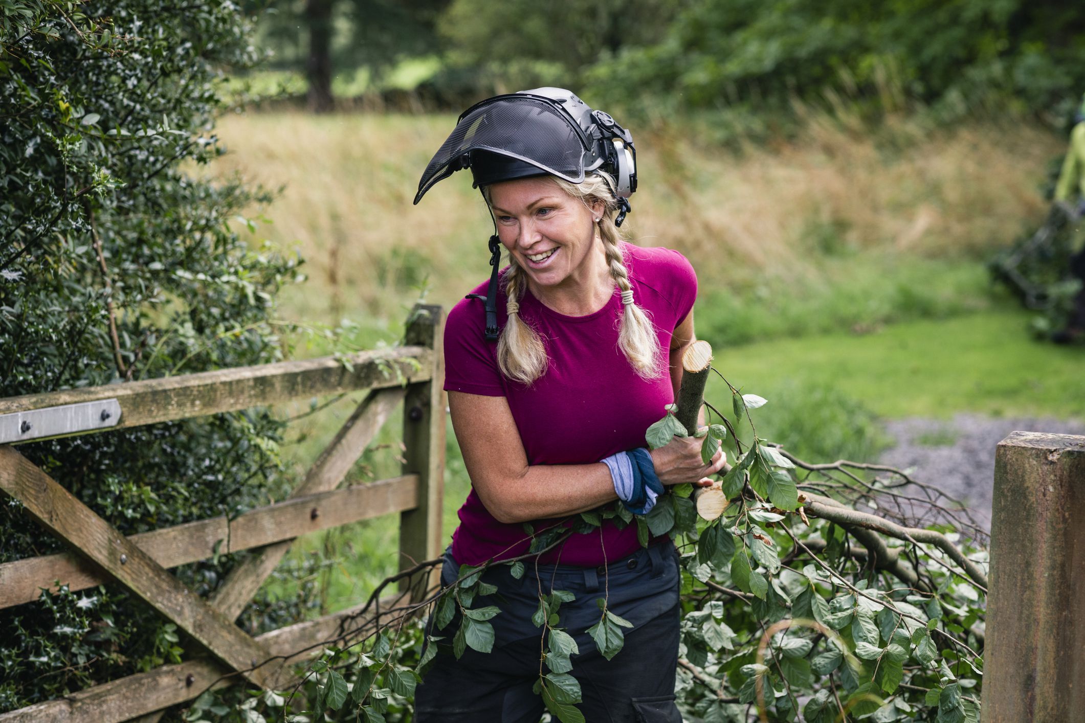Woman wearing safety helmet smiling and removing freshly felled tree