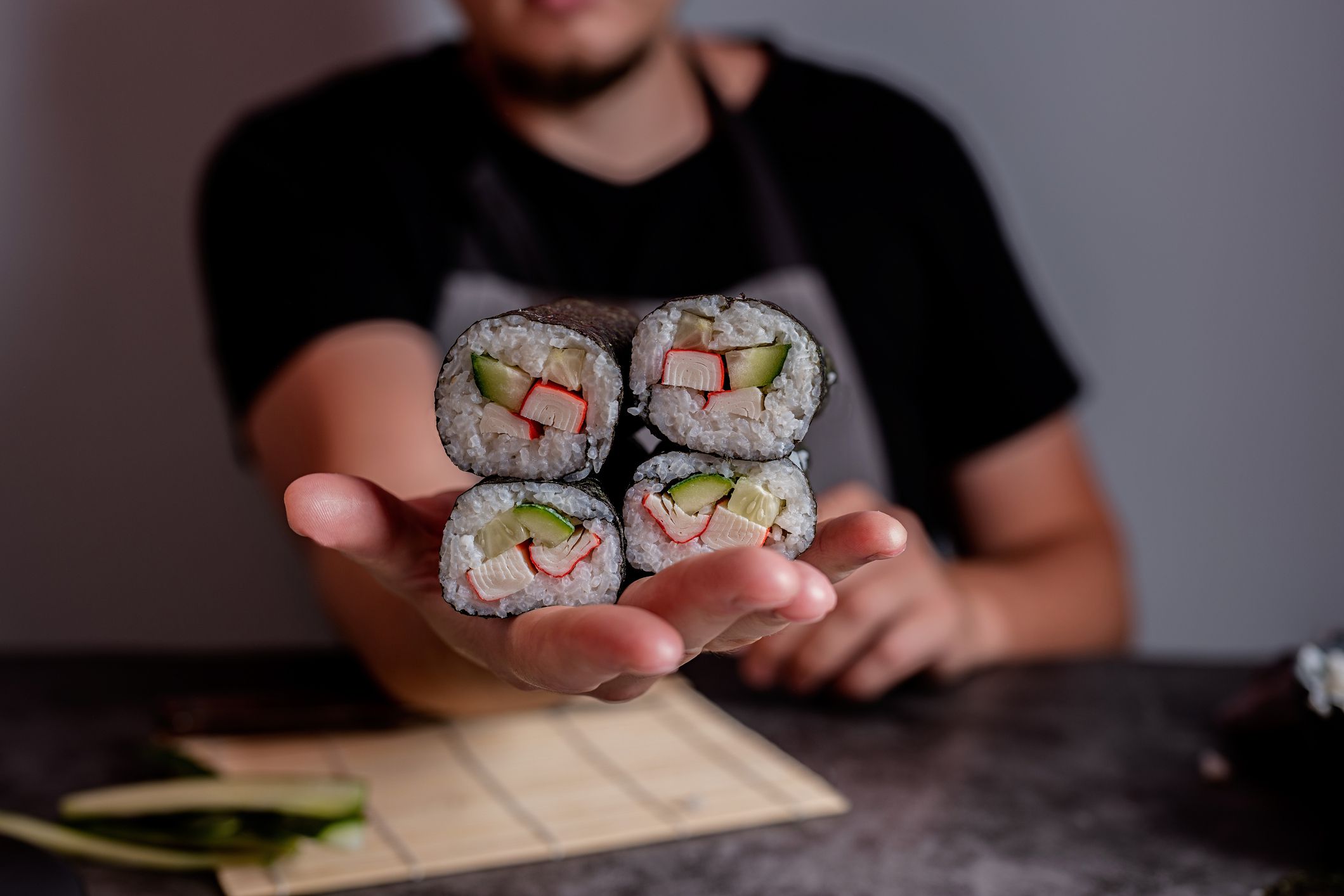 Man hands making homemade sushi rolls with crab meat and vegetables