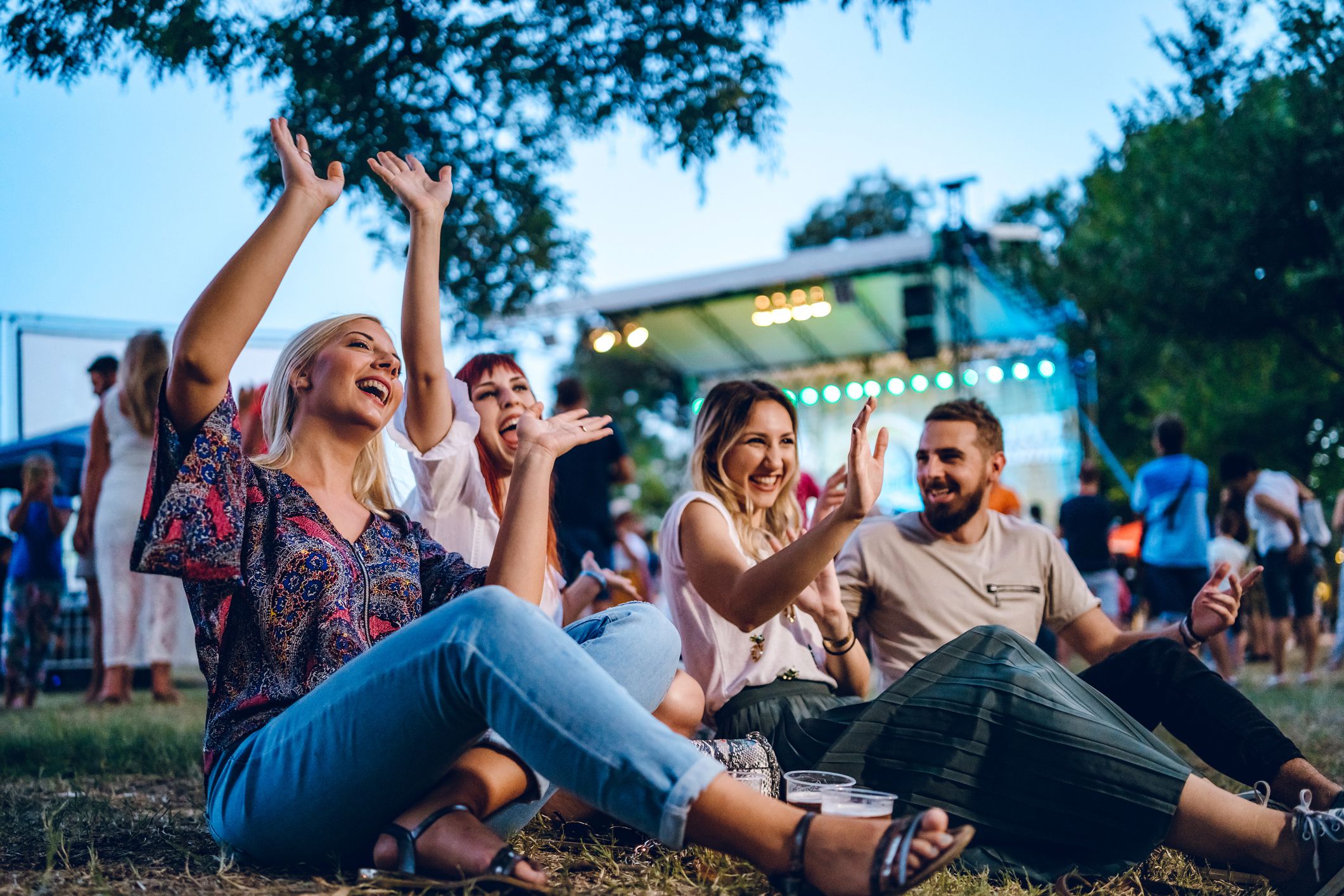Group of young Caucasian friends on a music festival sitting in a grass together.