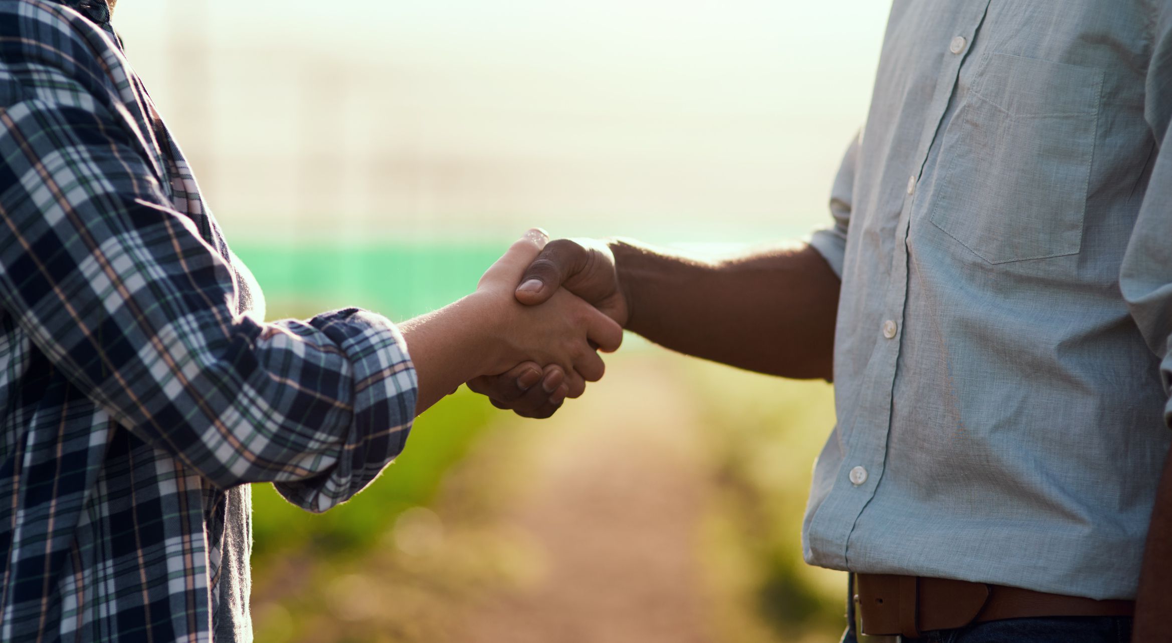 Cropped shot of two unrecognizable farmers shaking hands while working on their farm