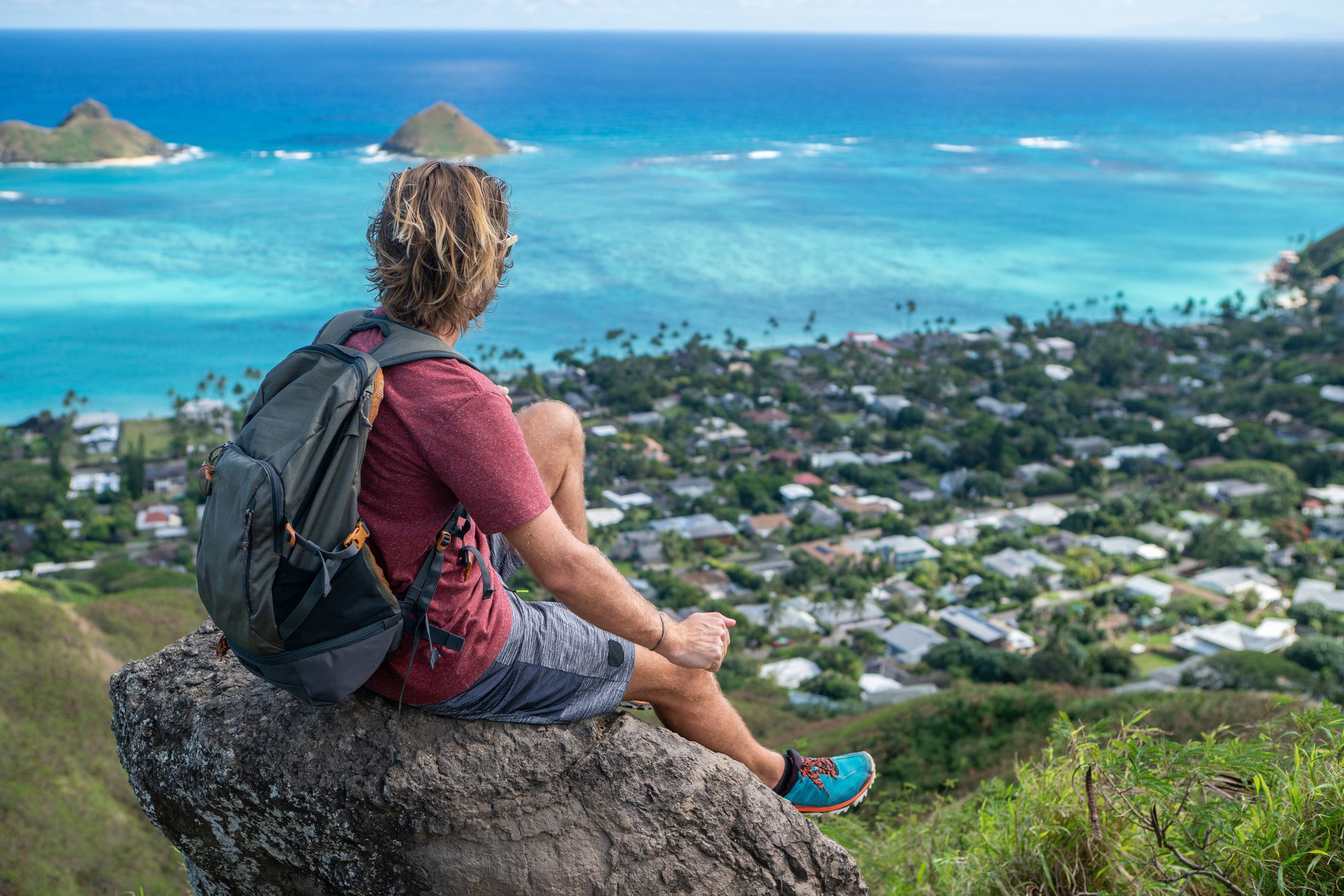 Man on mountain top overlooking the ocean and the reef on Oahu Island, Hawaii, USA. man contemplating the scenic view from hike